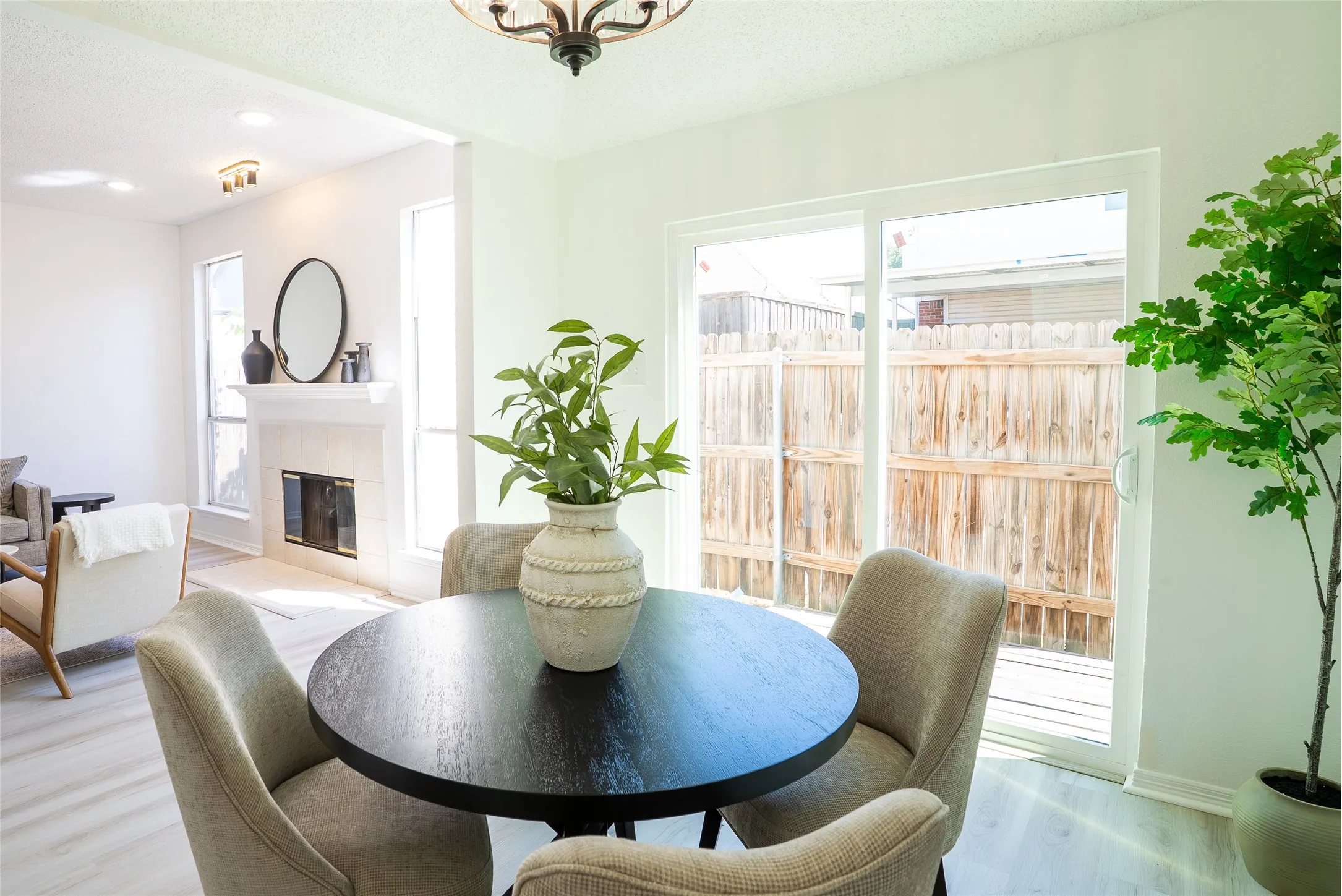 Light wood-finish flooring, white walls, and a white fireplace with a dark insert
