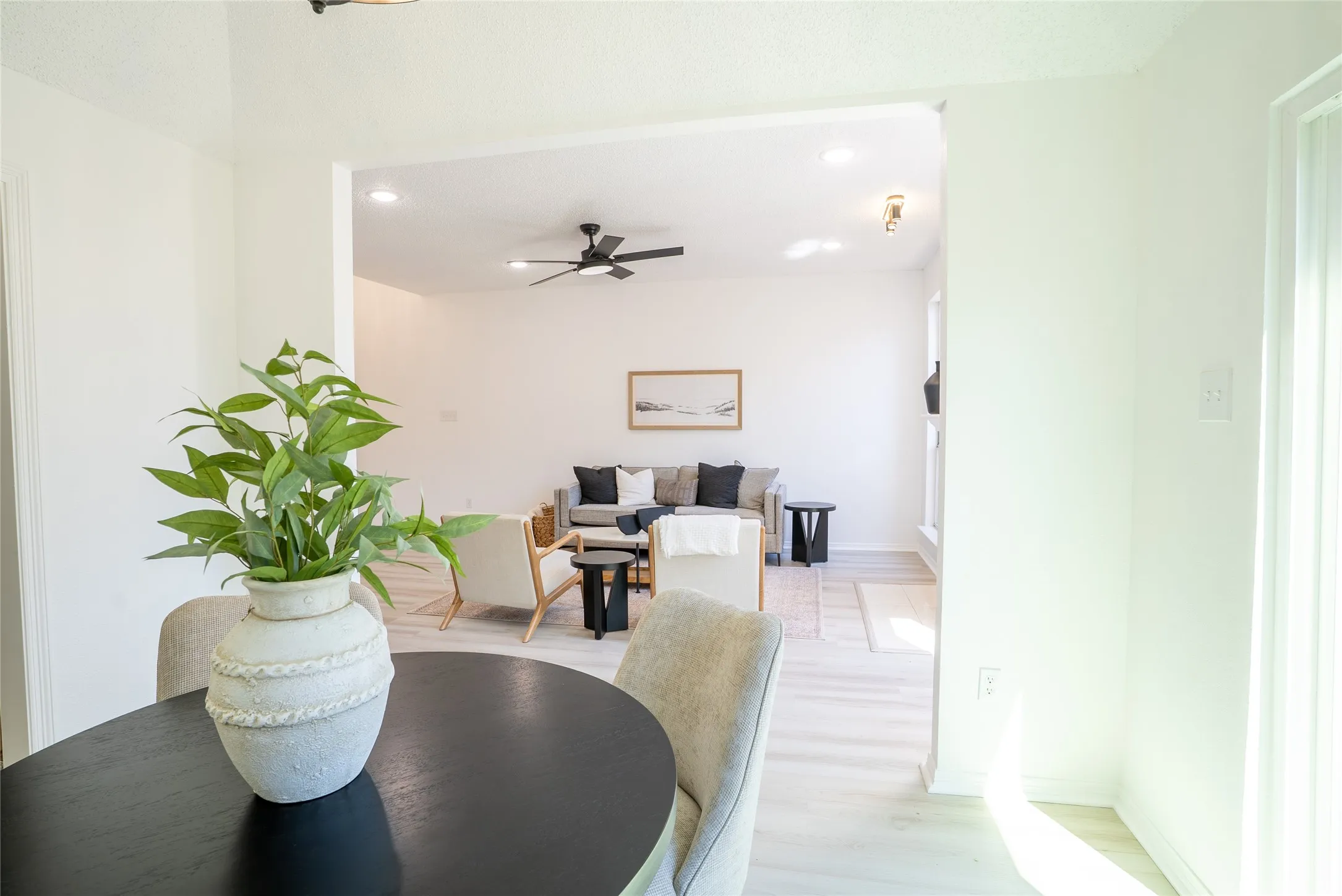 Open concept living space with light-toned wood-finish flooring and recessed lighting