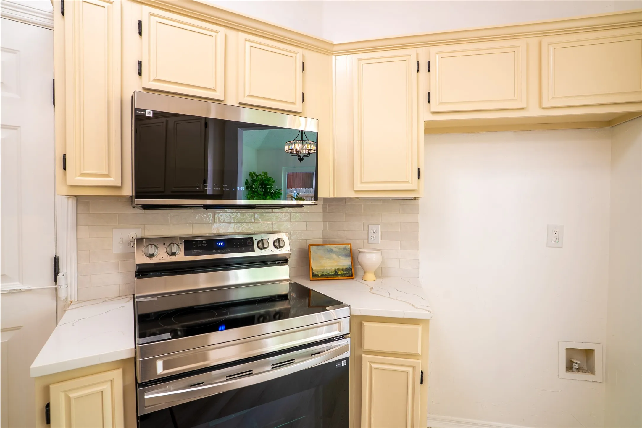 White subway tile backsplash, stainless steel electric range, and integrated microwave