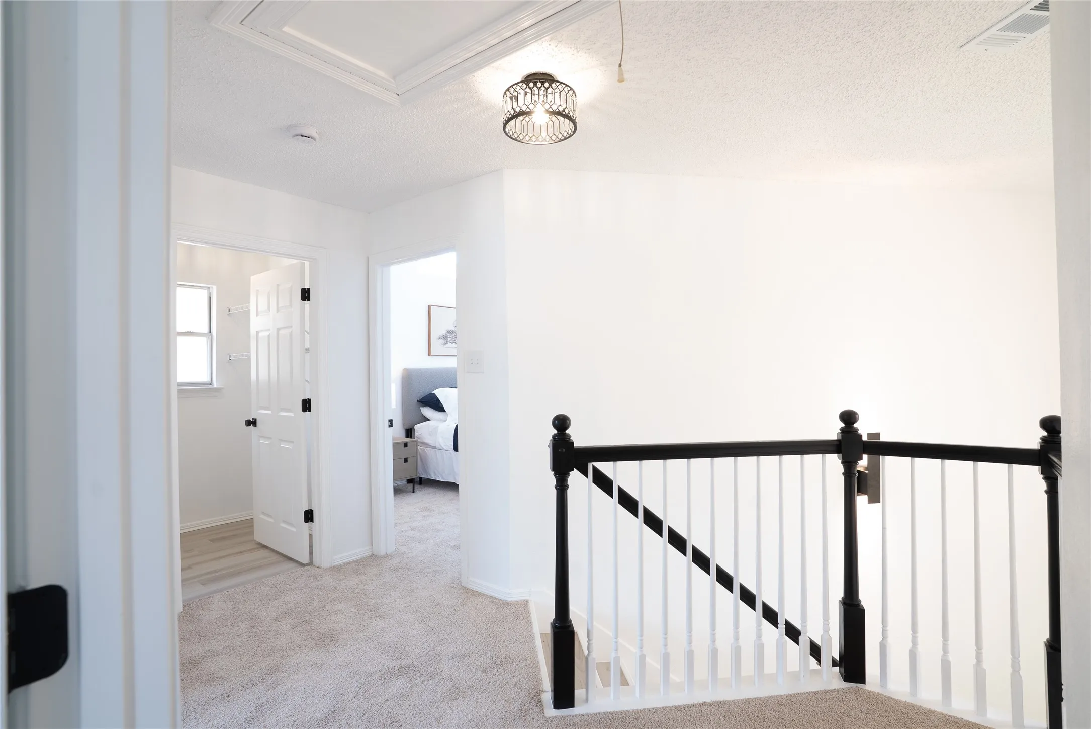 Staircase with black newel posts and handrail, white balusters, and light-toned carpet