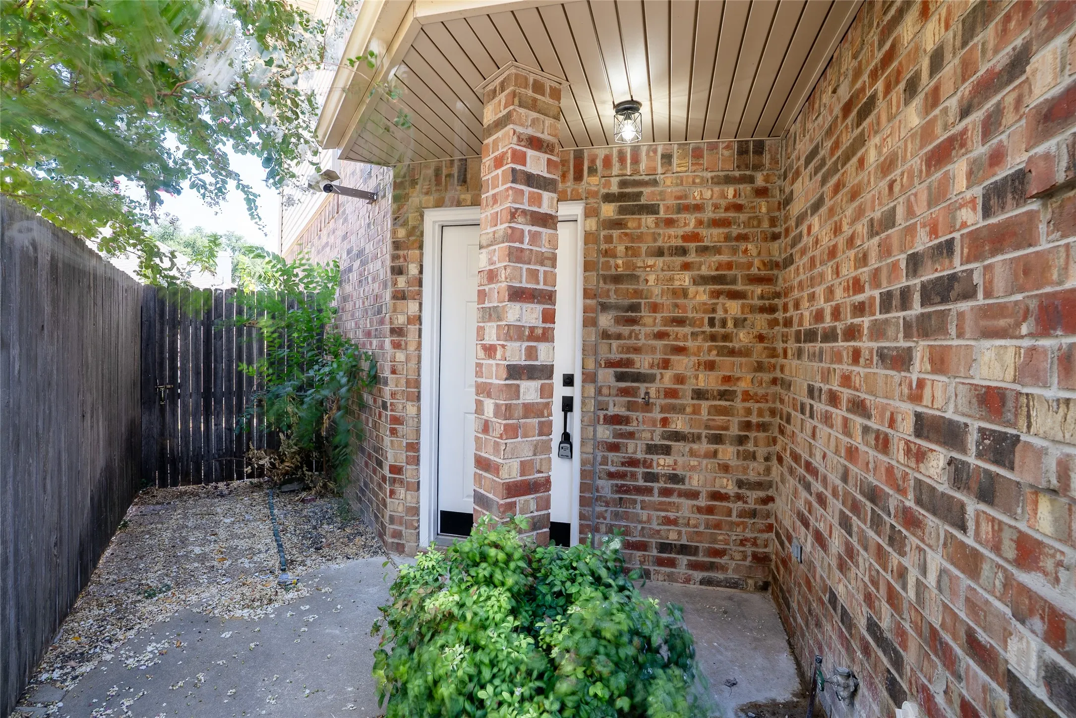 Brick exterior with a covered entry, overhead lighting, and a white entry door