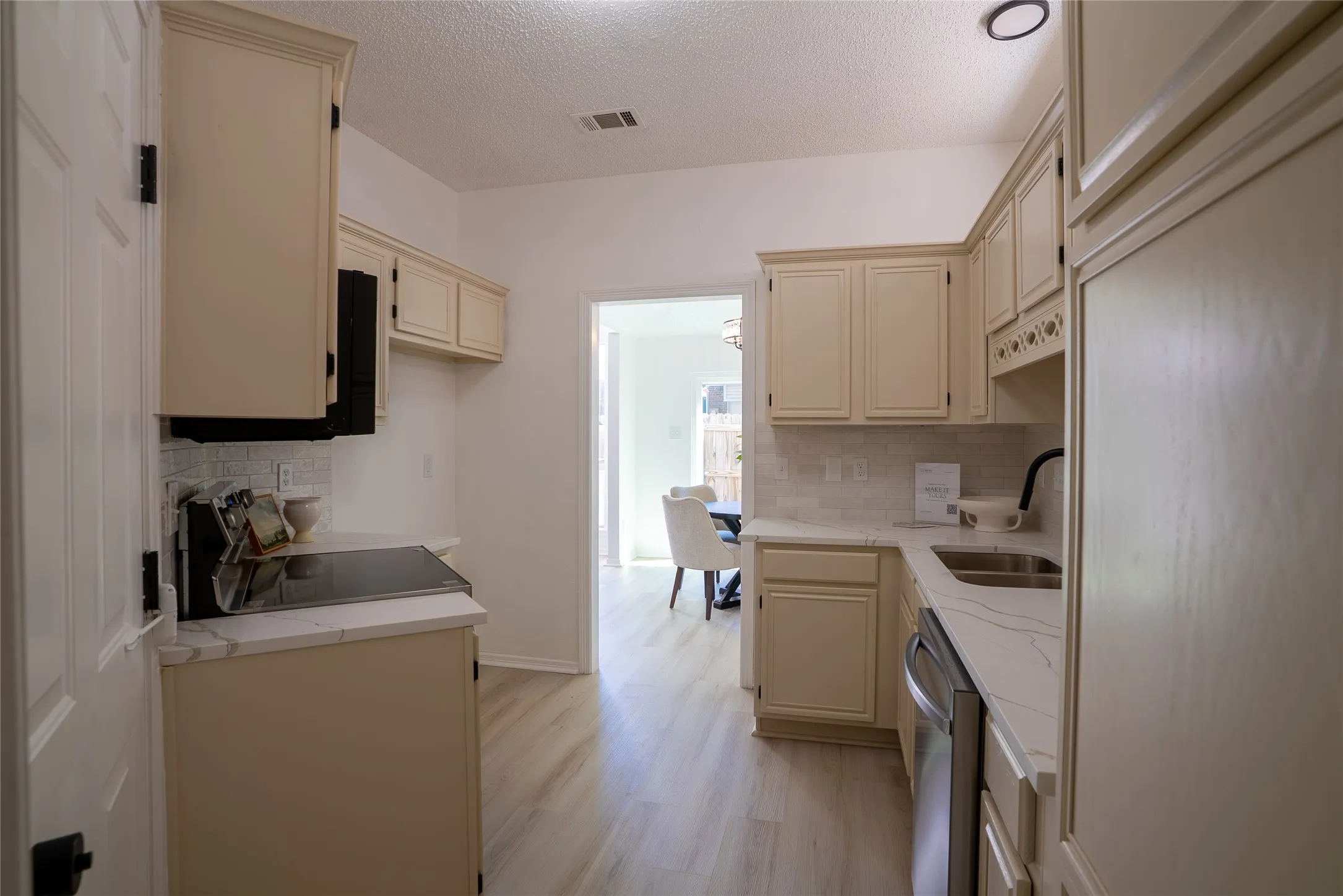 Kitchen featuring cream cabinetry, tile backsplash, light wood-finish flooring, and white countertops