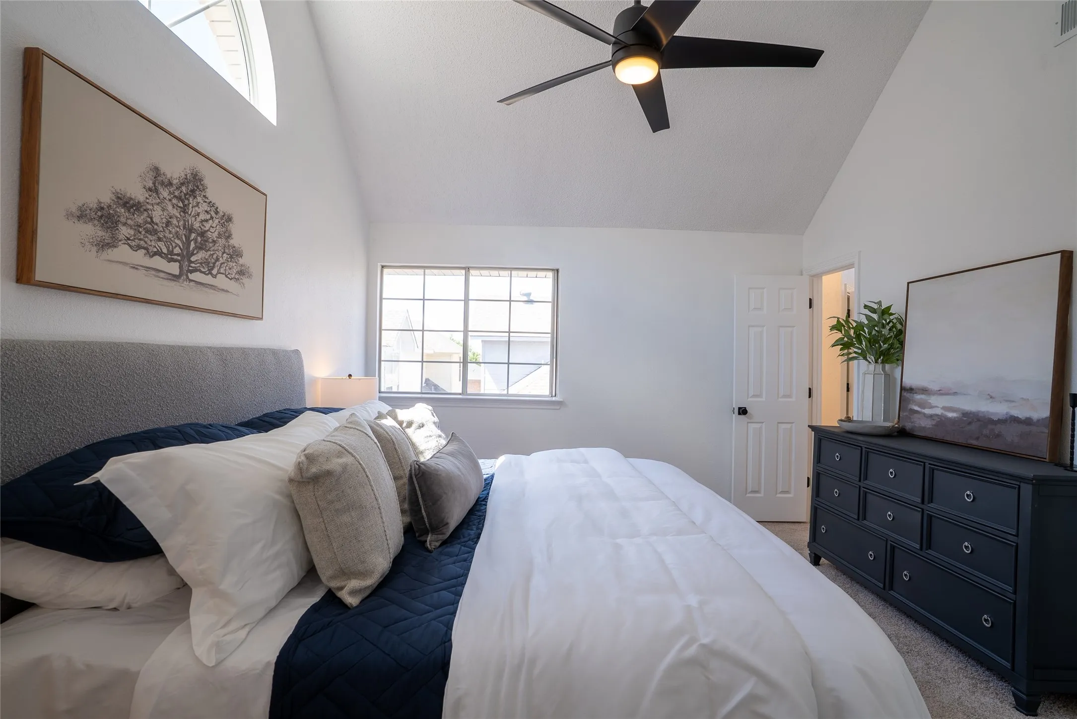 Vaulted ceiling with an arched window and a ceiling fan