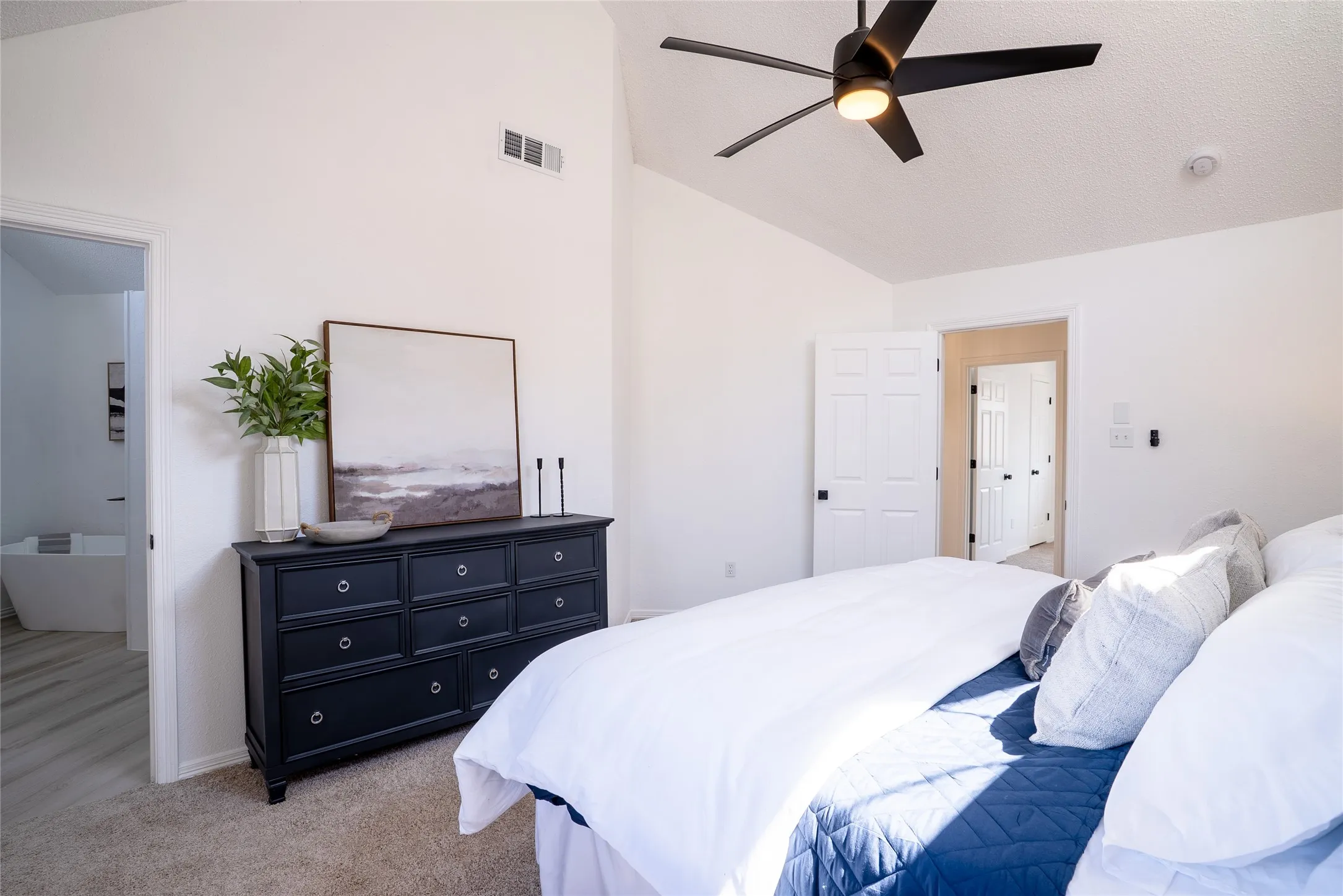 Vaulted ceilings, a contemporary ceiling fan, and light-colored carpeting