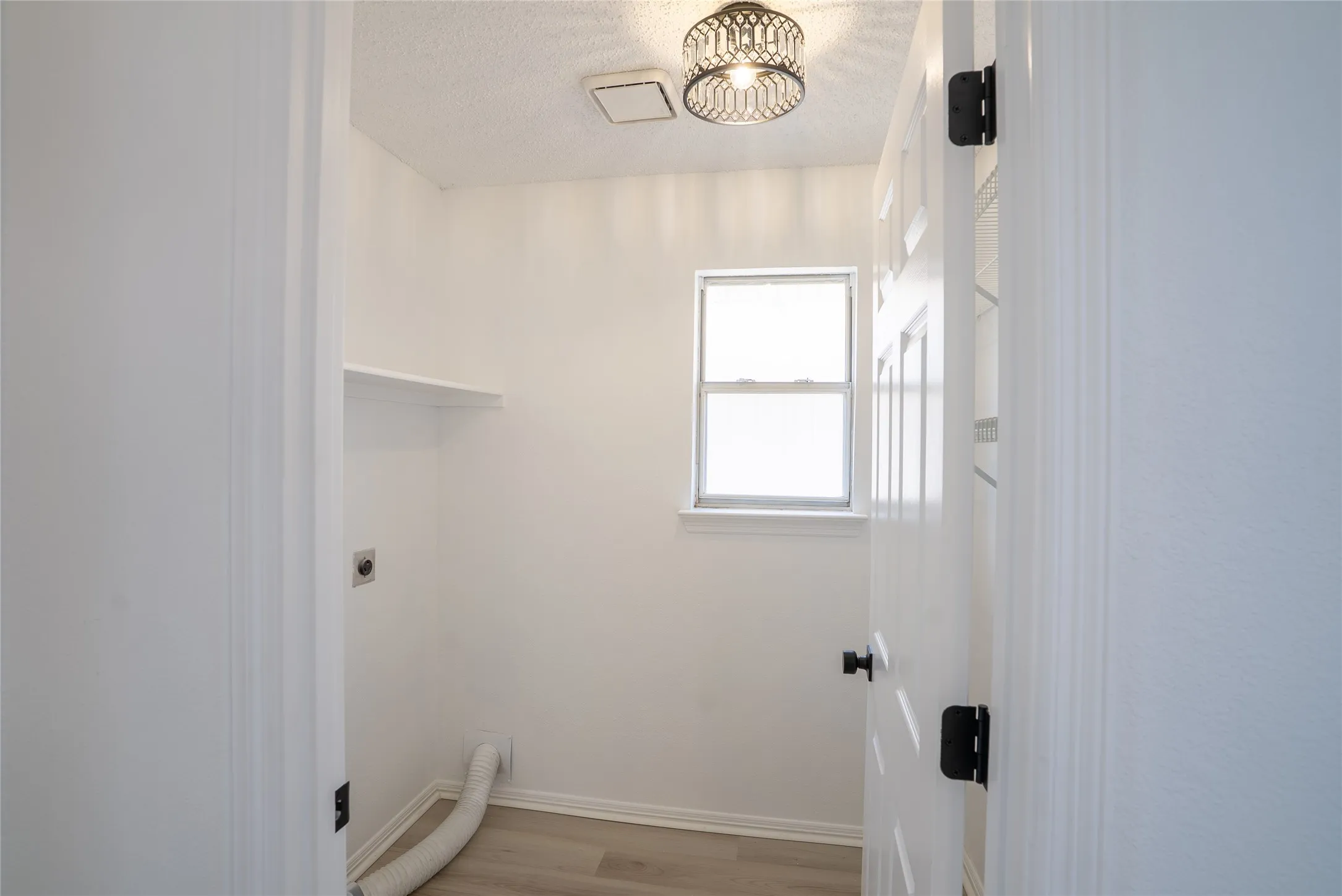 Utility room featuring a window, built-in shelving, and wood-finish flooring