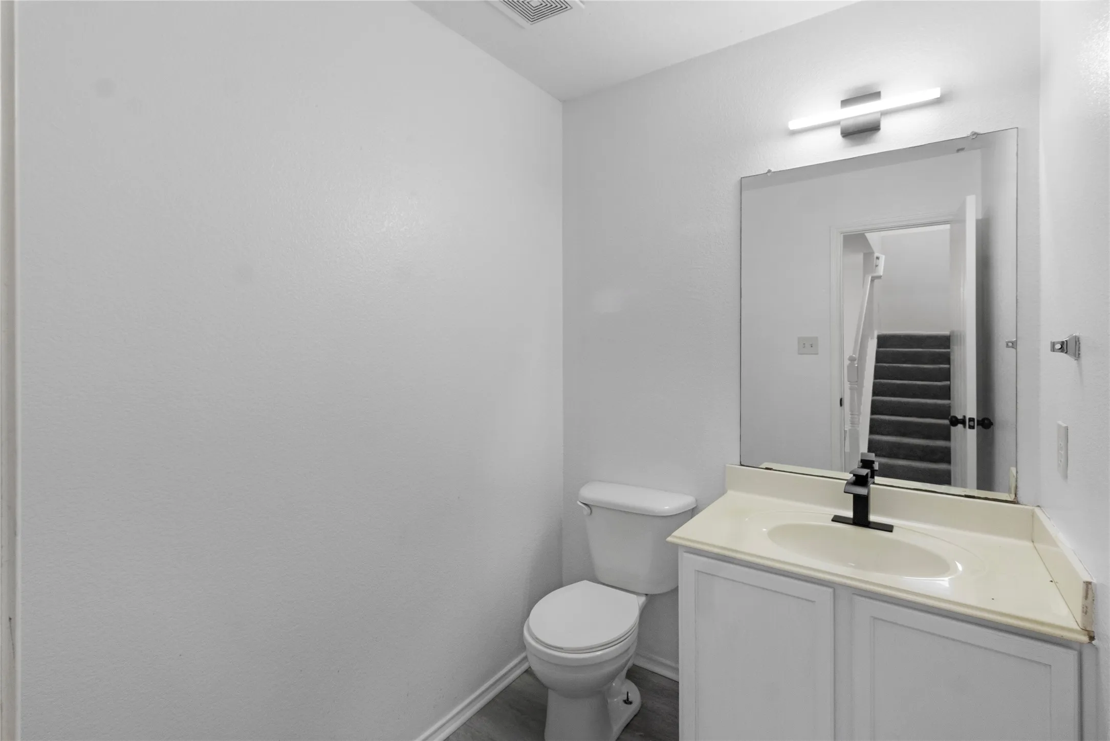 White vanity with white cabinets, light-toned countertop, and a rectangular undermount sink
