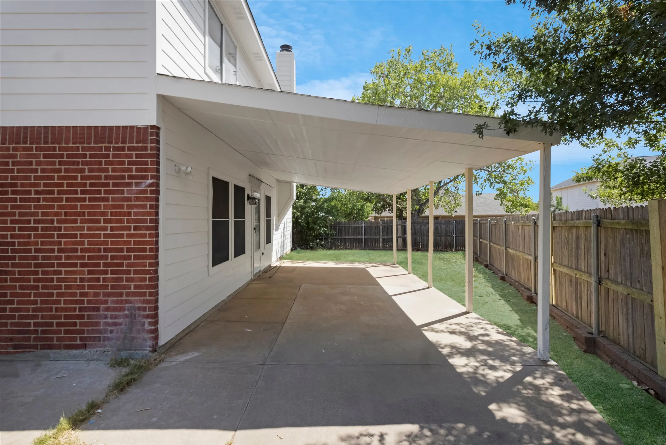 Expansive concrete patio with a covered outdoor area, offering direct access to the interior