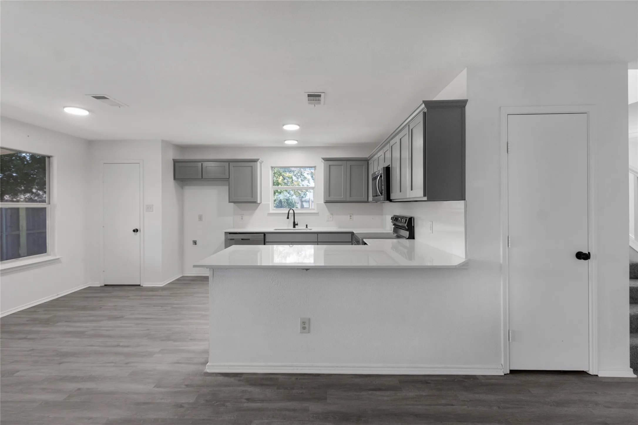 Kitchen featuring white countertops, gray cabinetry, a white subway tile backsplash, and black appliances
