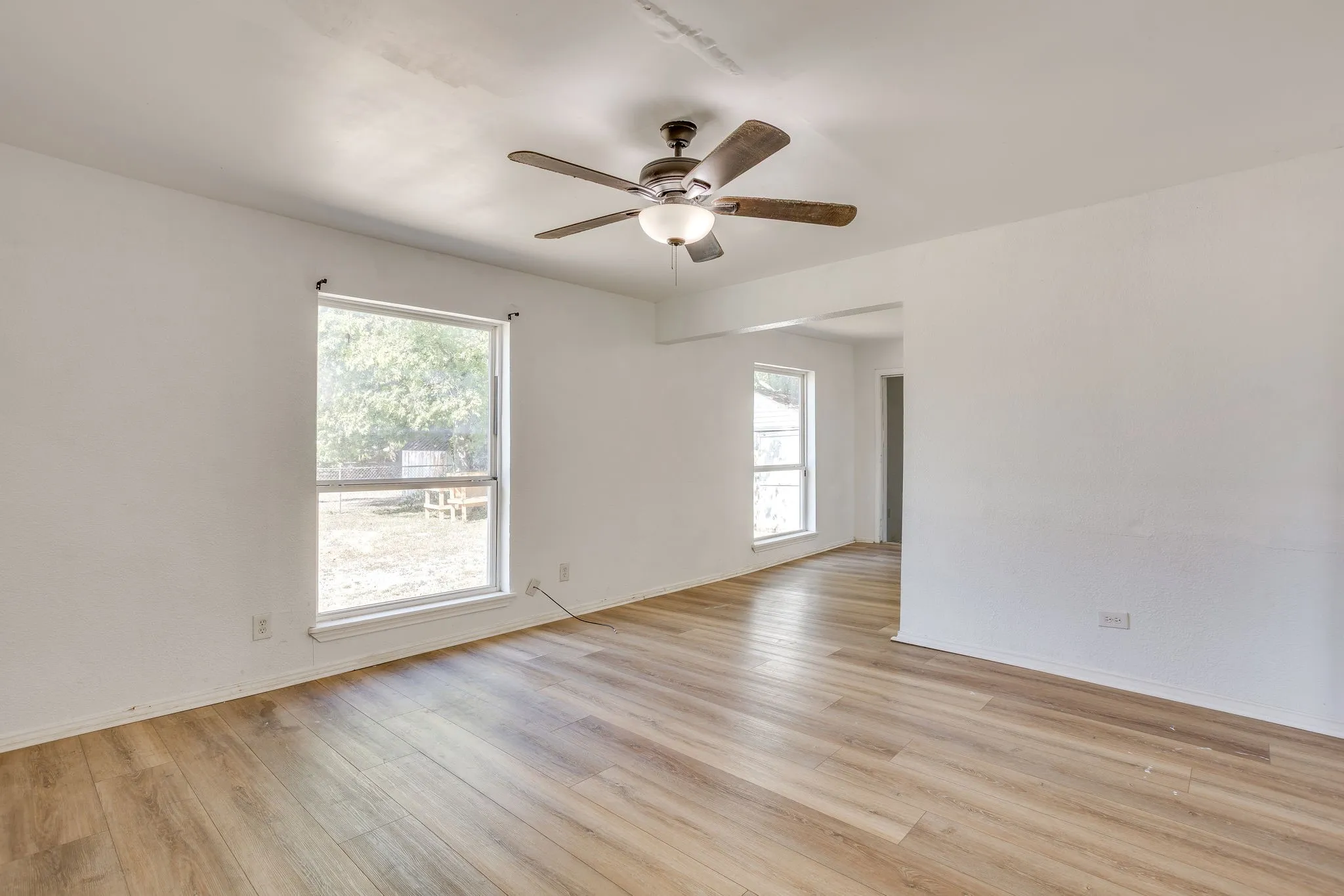 Living room with laminate flooring, ceiling fan, and great natural light!