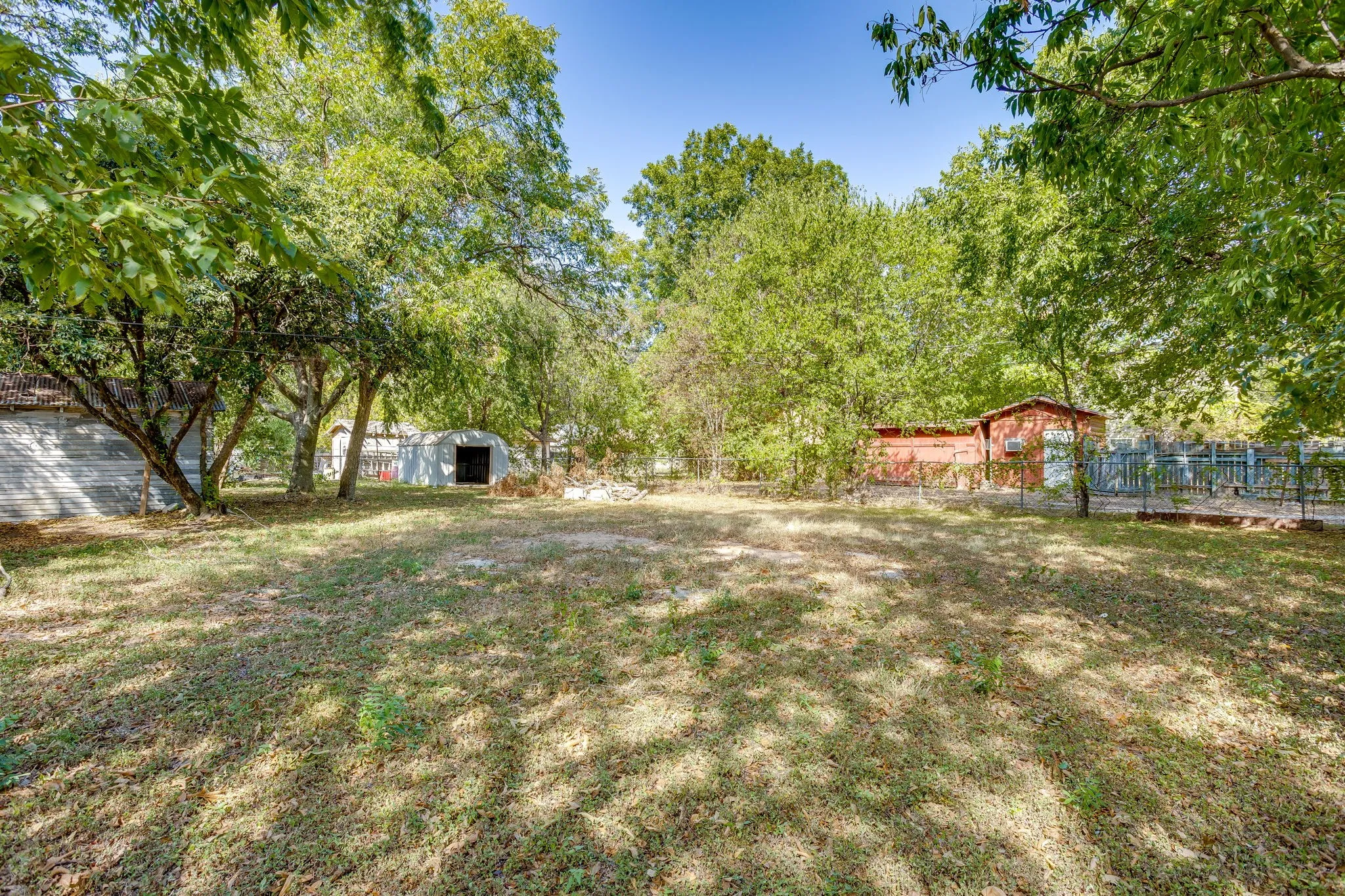 Large backyard fully fenced with chain link fence and storage shed.