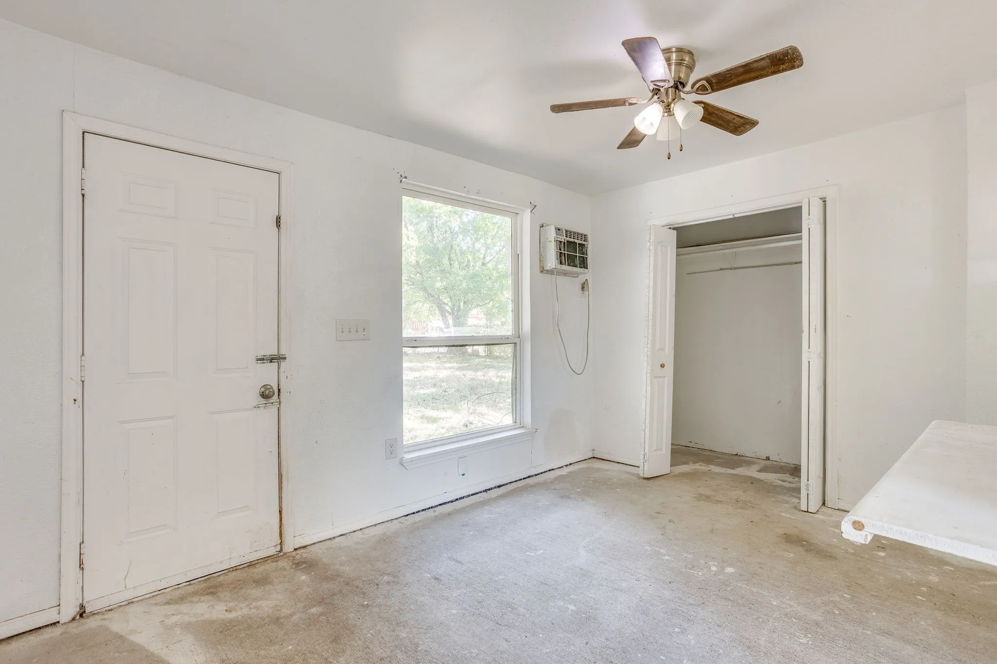 Utility space with concrete flooring-enclosed and vented into main system, ceiling fan and closet for additional storage.