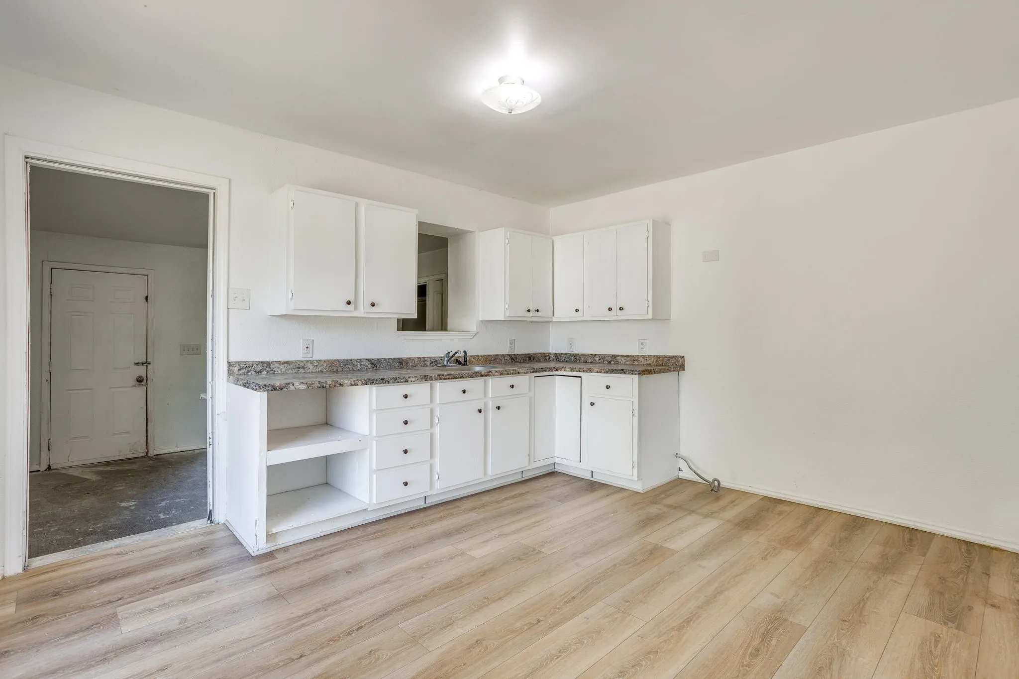 Kitchen with painted white cabinets and plenty of room to work and store items. Open to enclosed back porch that serves as a utility room.