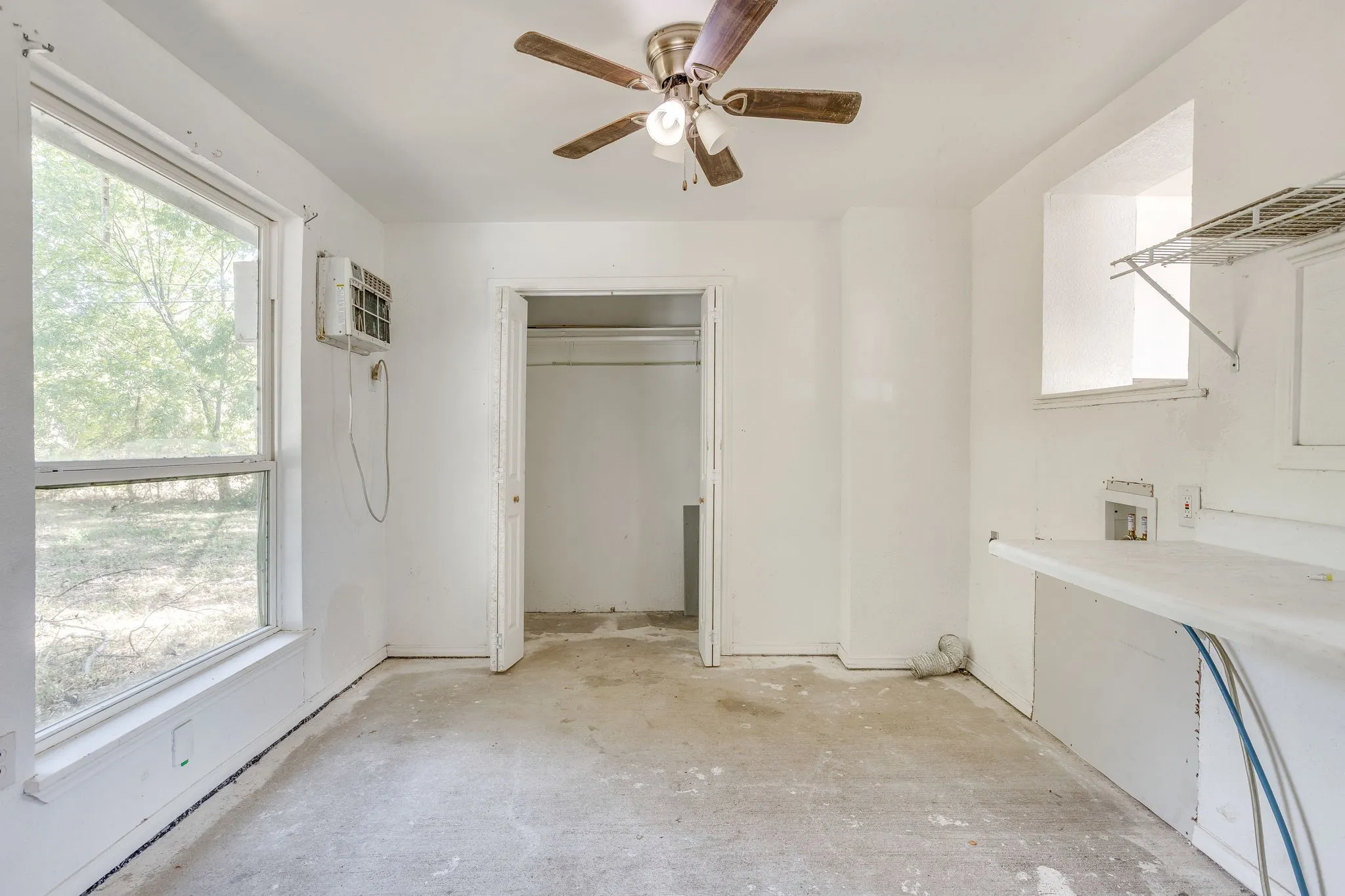 Utility space with electric hook up for washer and dryer now enclosed with shelving, closet and ceiling fan.