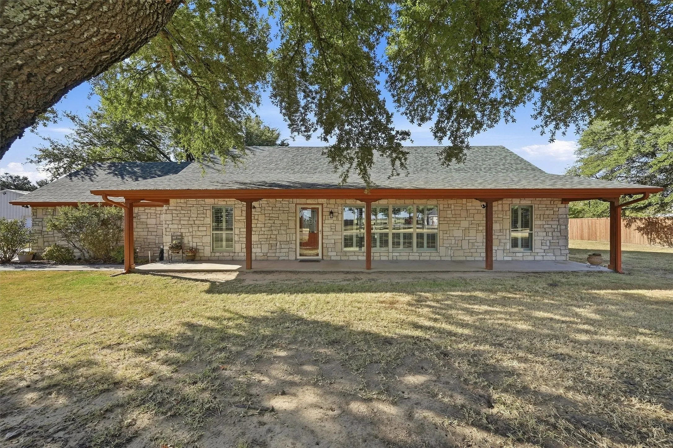 Stone facade with a covered patio, supported by wooden columns