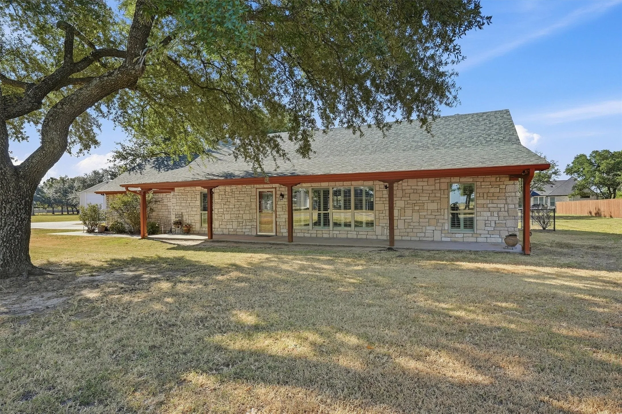 Stone exterior with a covered front porch, large windows, and a mature tree