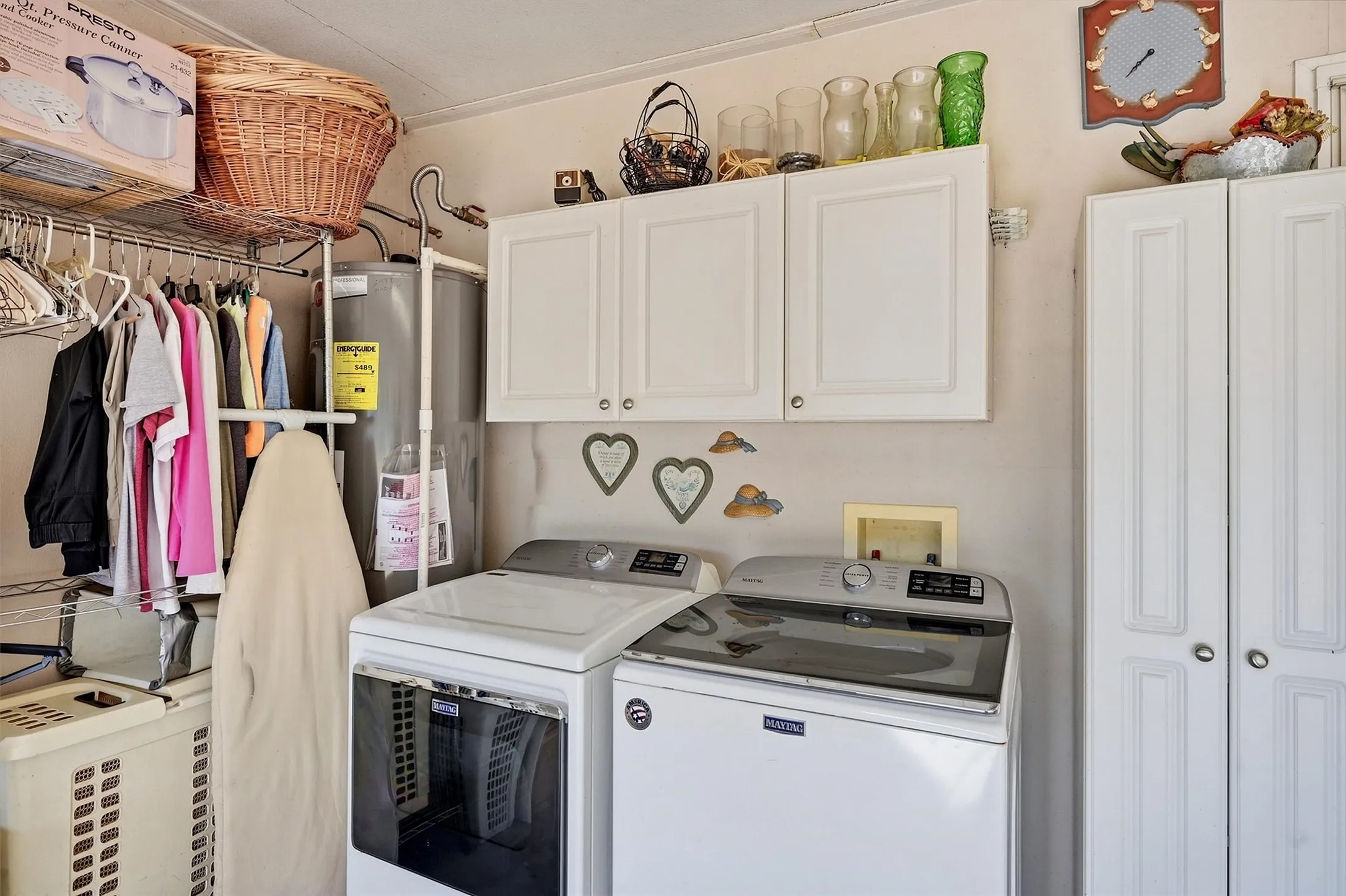 White upper cabinetry, white bifold storage doors, wire shelving, and a water heater