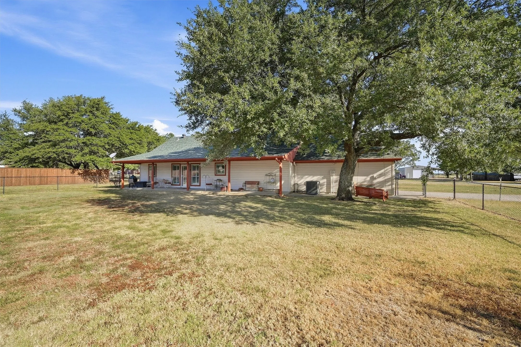 Expansive yard featuring mature trees, a covered patio, and a wood privacy fence