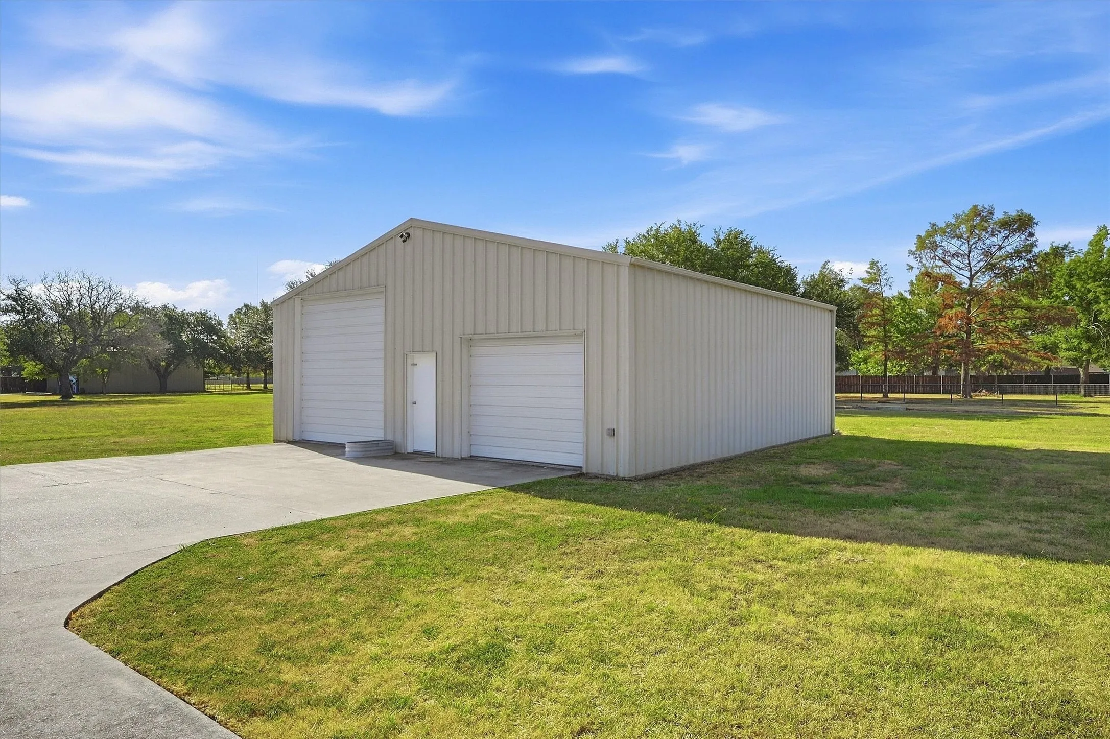 Metal construction building with a pitched roof, two roll-up doors, and an additional pedestrian entry