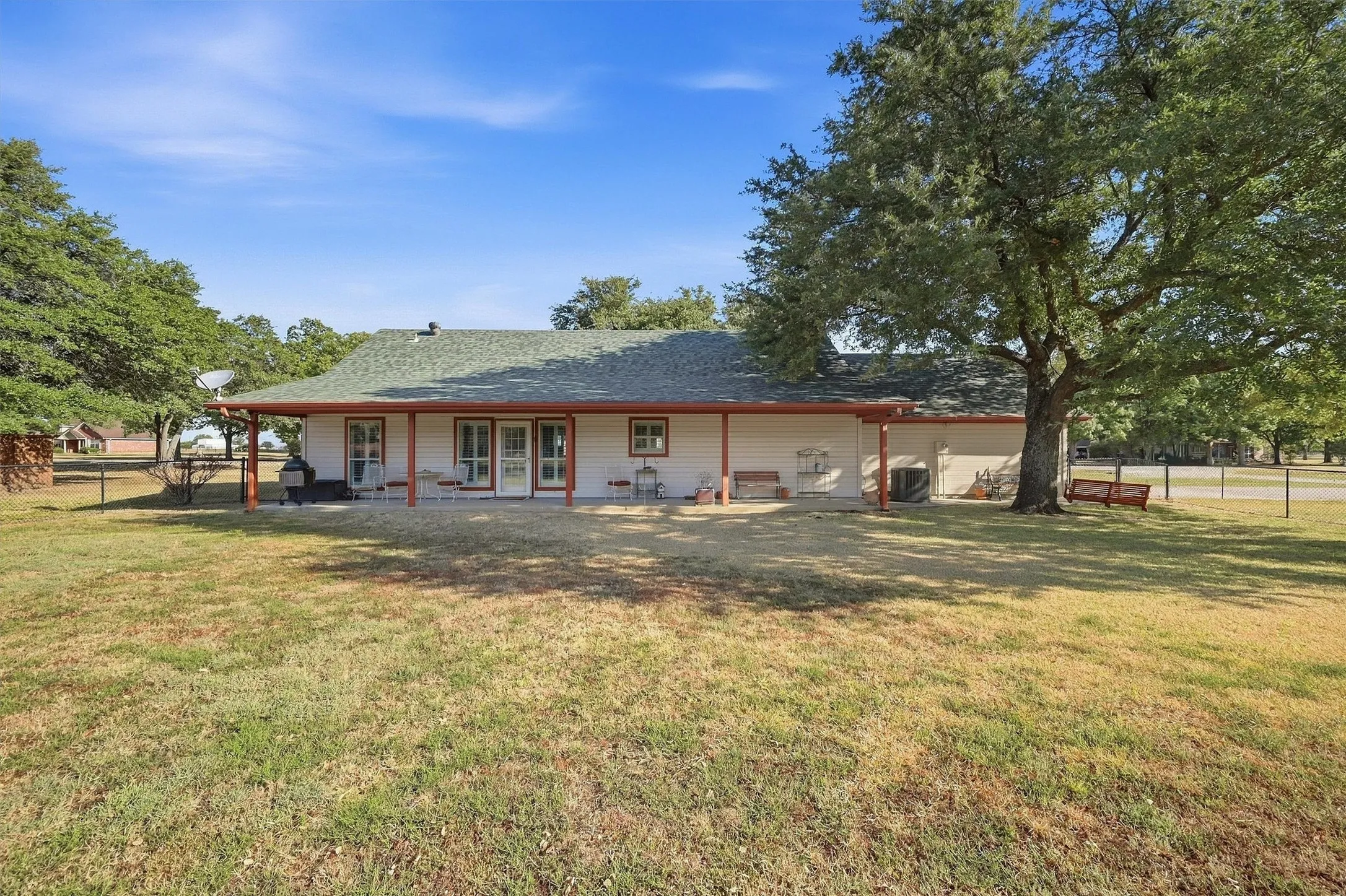Expansive backyard with a covered patio, multiple exterior doors, and mature trees