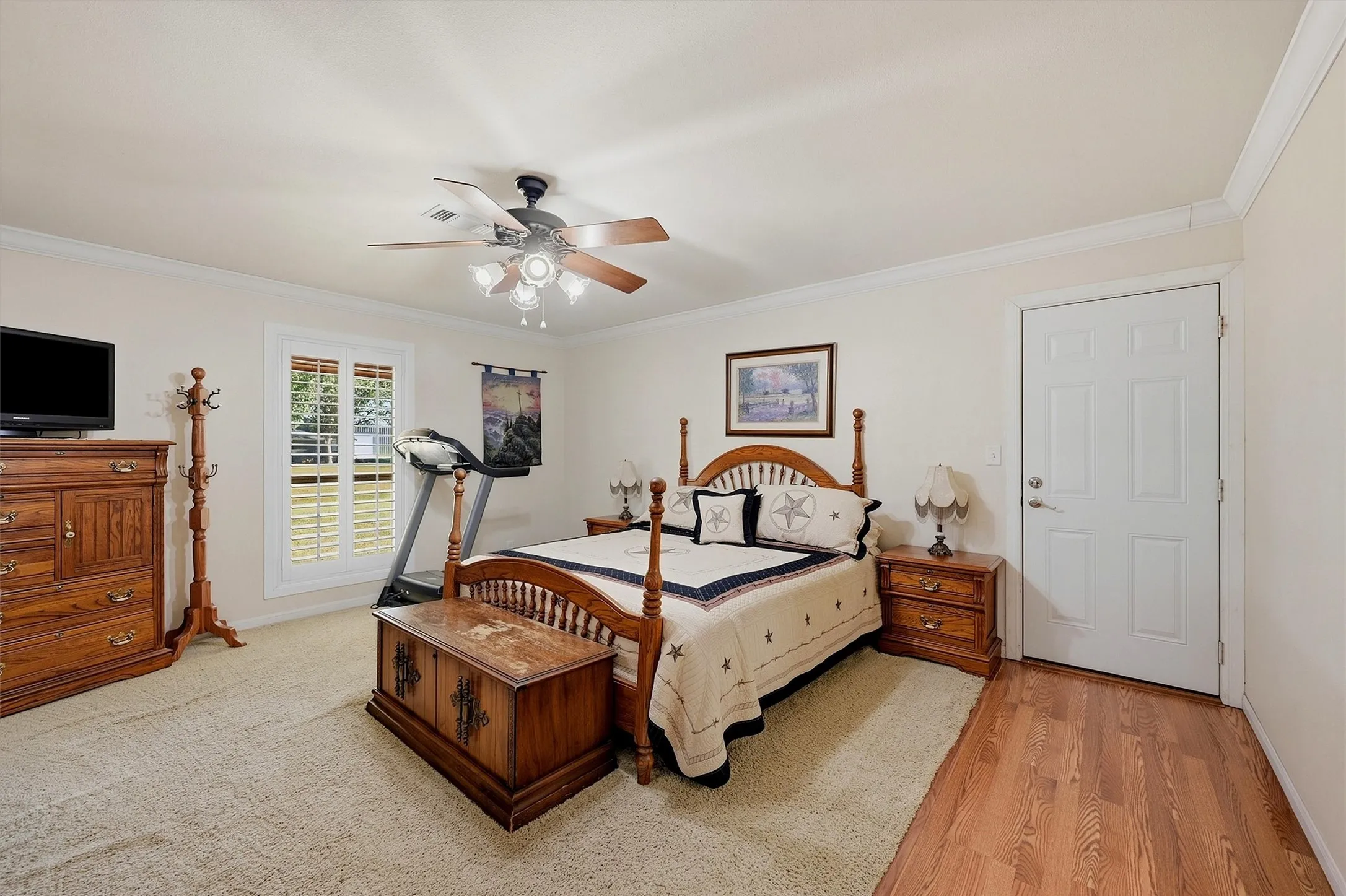 Tray ceiling with a ceiling fan, crown molding, and window with plantation shutters