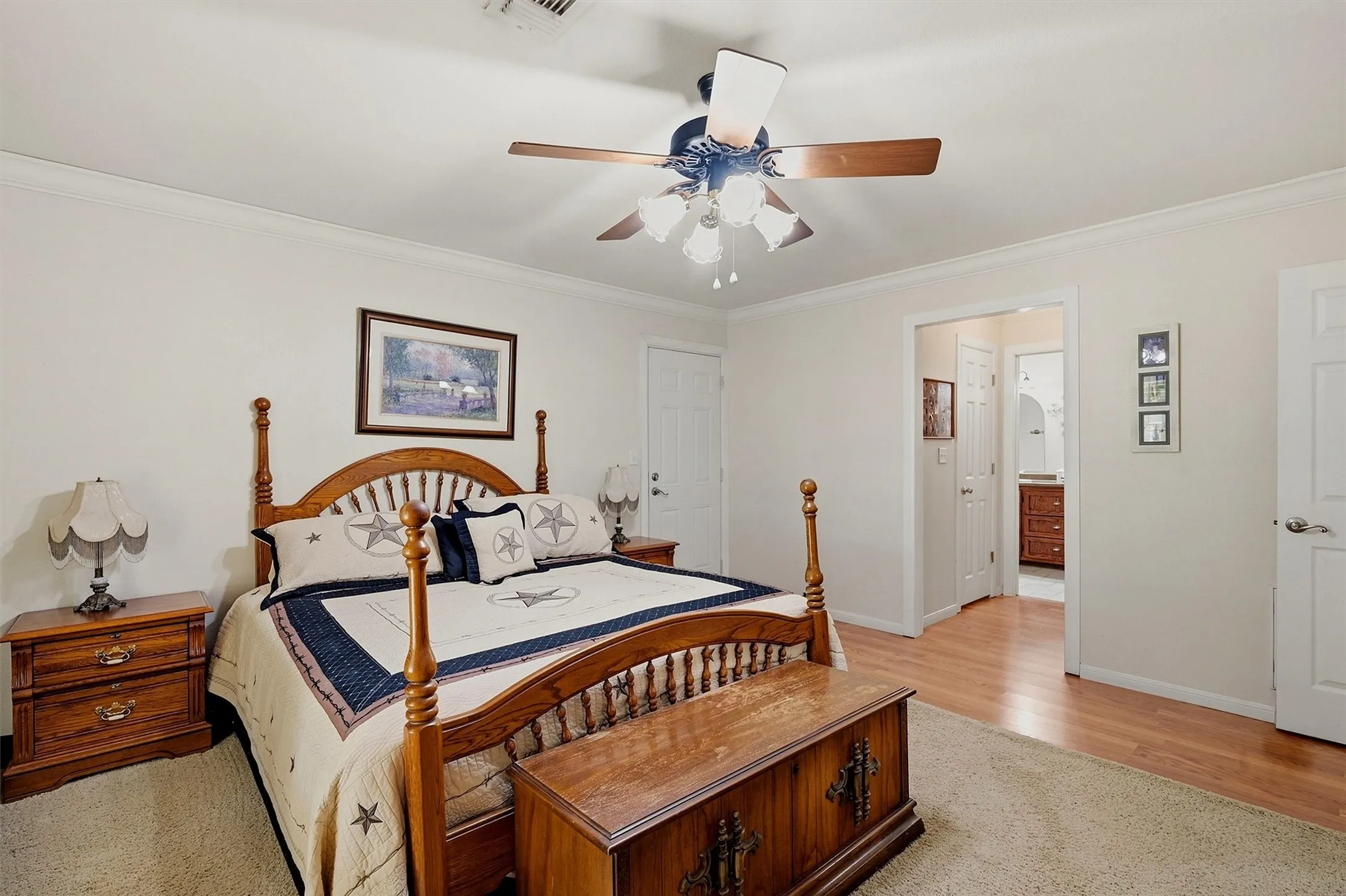 White walls with crown molding, wood-finish flooring, and a ceiling fan with integrated lighting