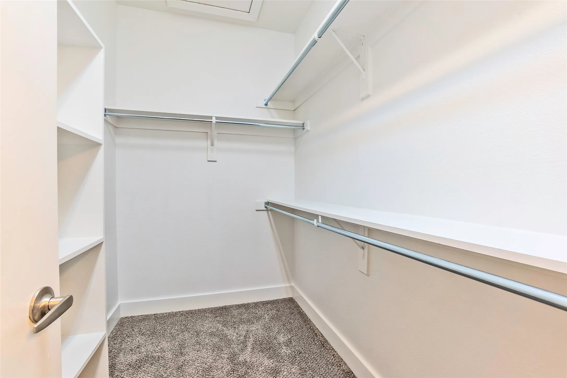 Built-in shelving, chrome hanging rods, and plush gray carpeting