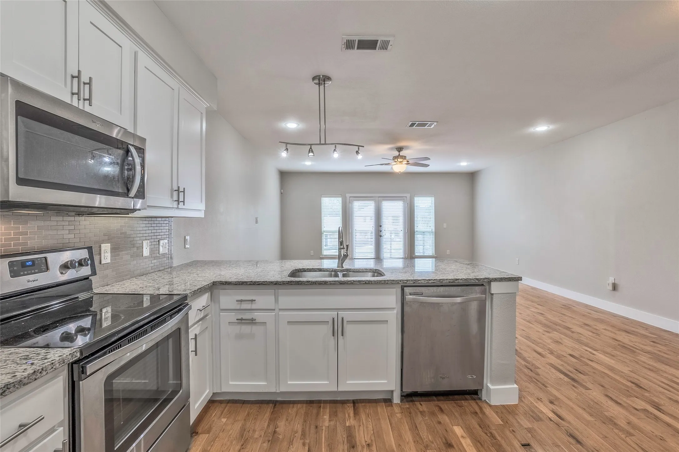 Kitchen featuring white cabinetry, stainless steel appliances, granite countertops, and a tiled backsplash