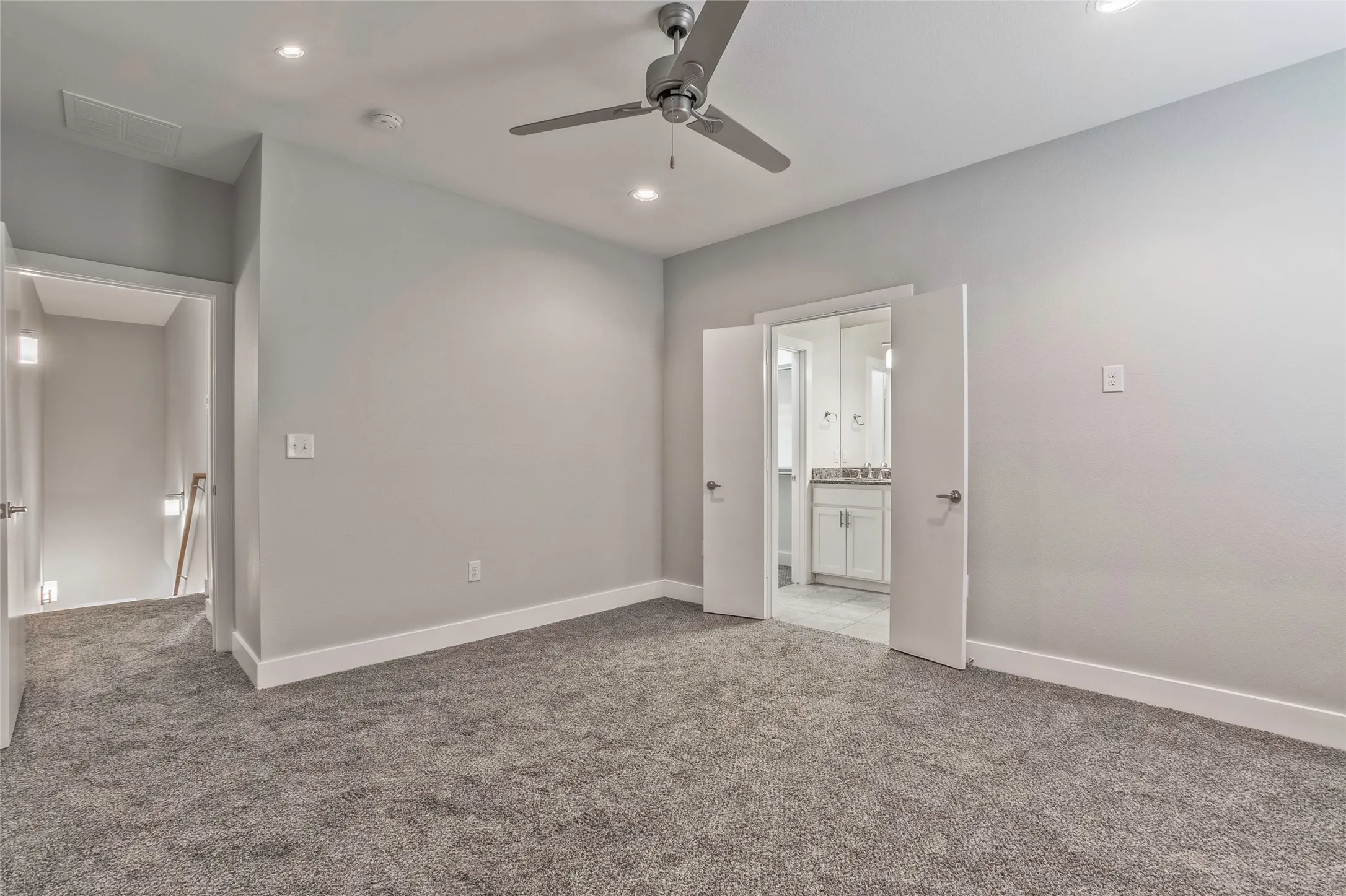 Plush carpeted room featuring a ceiling fan, recessed lighting, and direct access to a bathroom with a dual vanity and framed mirror