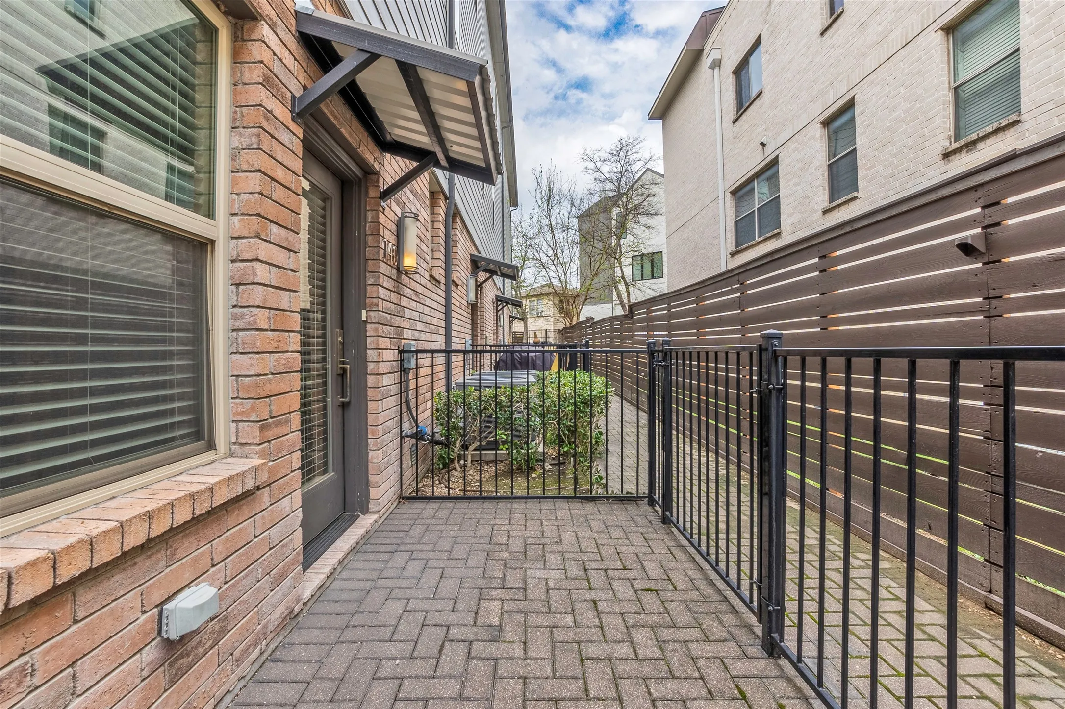 Brick exterior with a metal awning, featuring an outdoor wall sconce, and a glass-paneled door