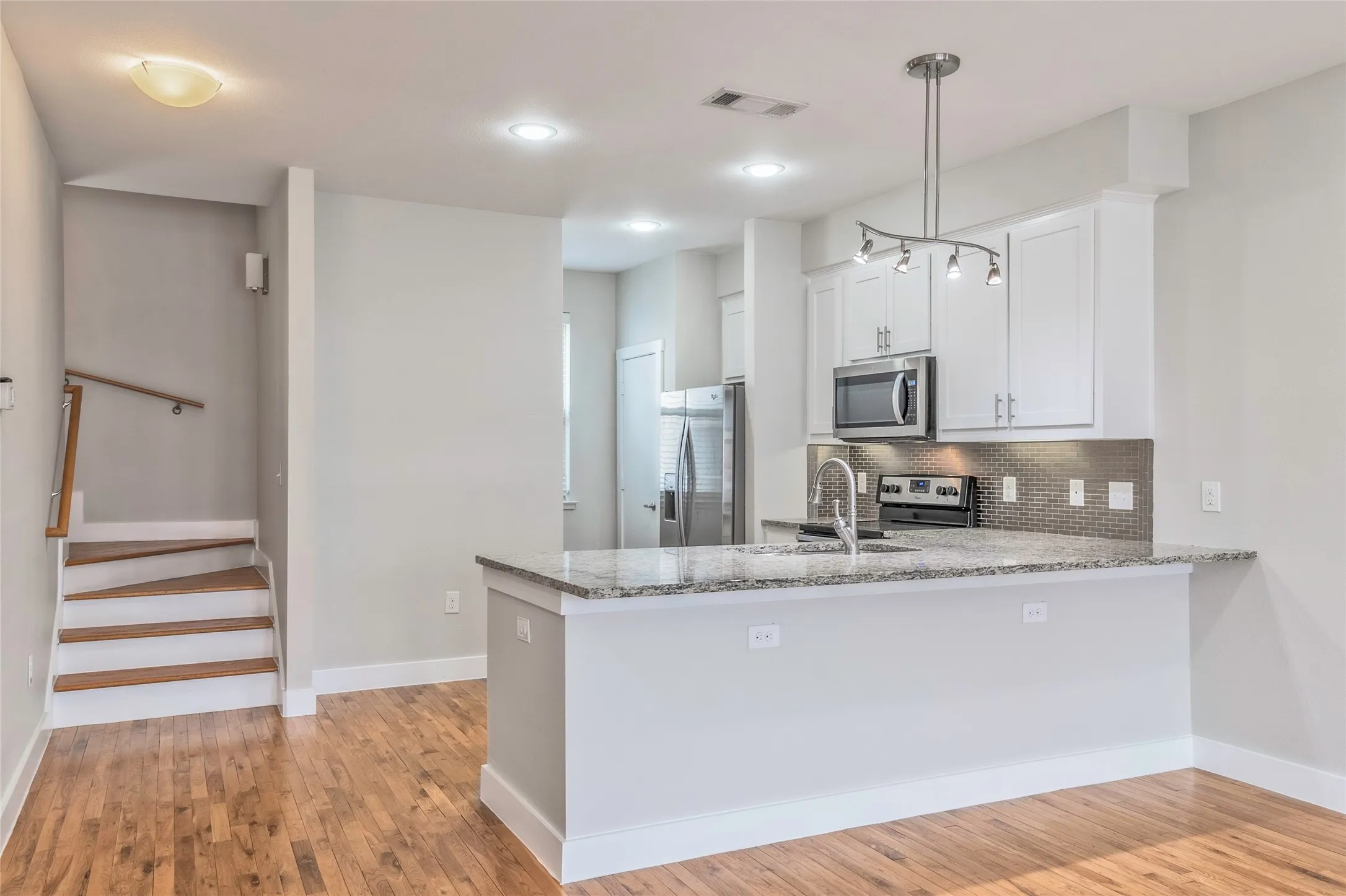 Kitchen featuring white cabinetry, stainless steel appliances, granite countertops, and a tile backsplash