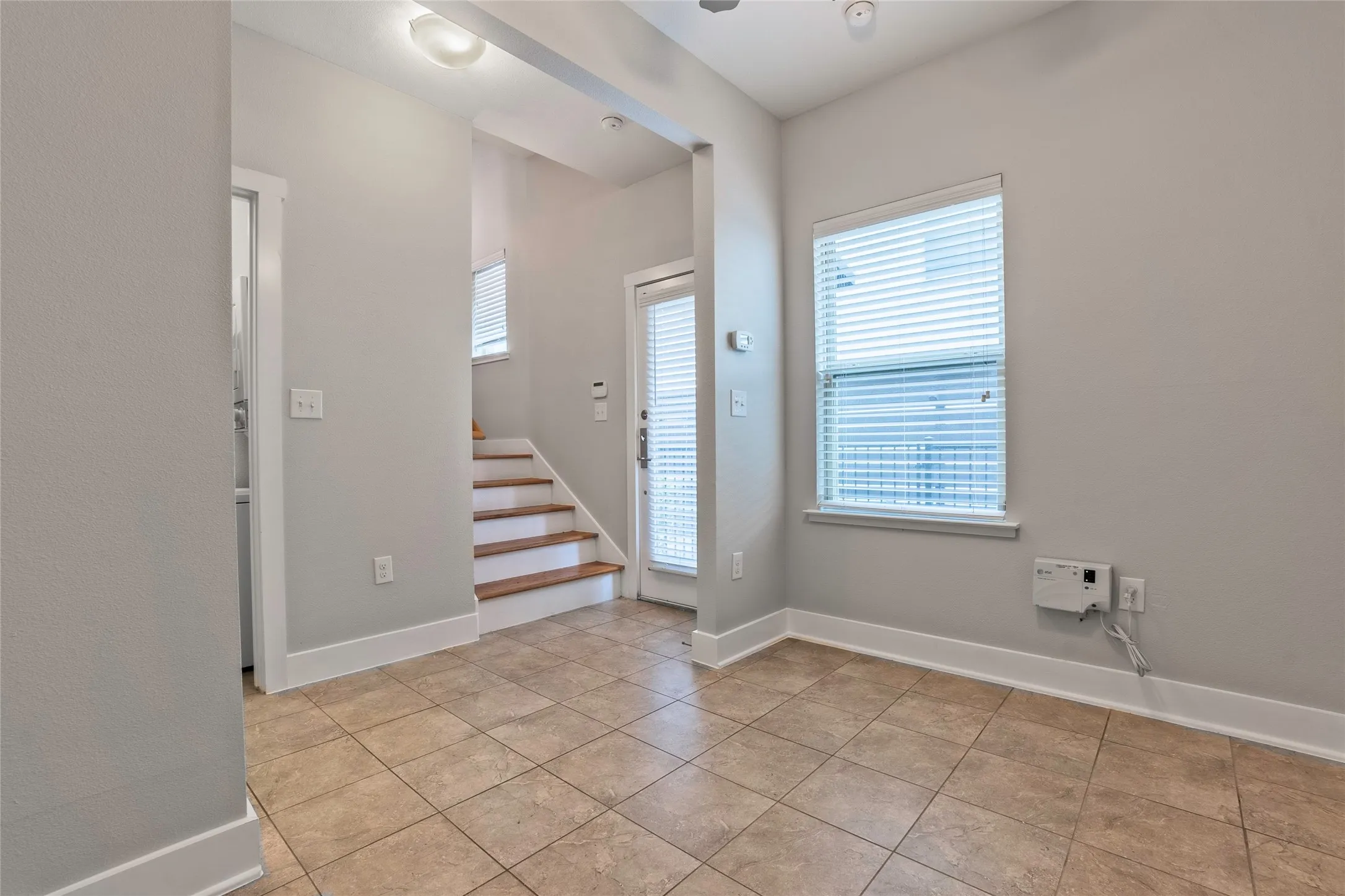 Neutral wall color, tile flooring, wood-finish stair treads, and a white paneled door