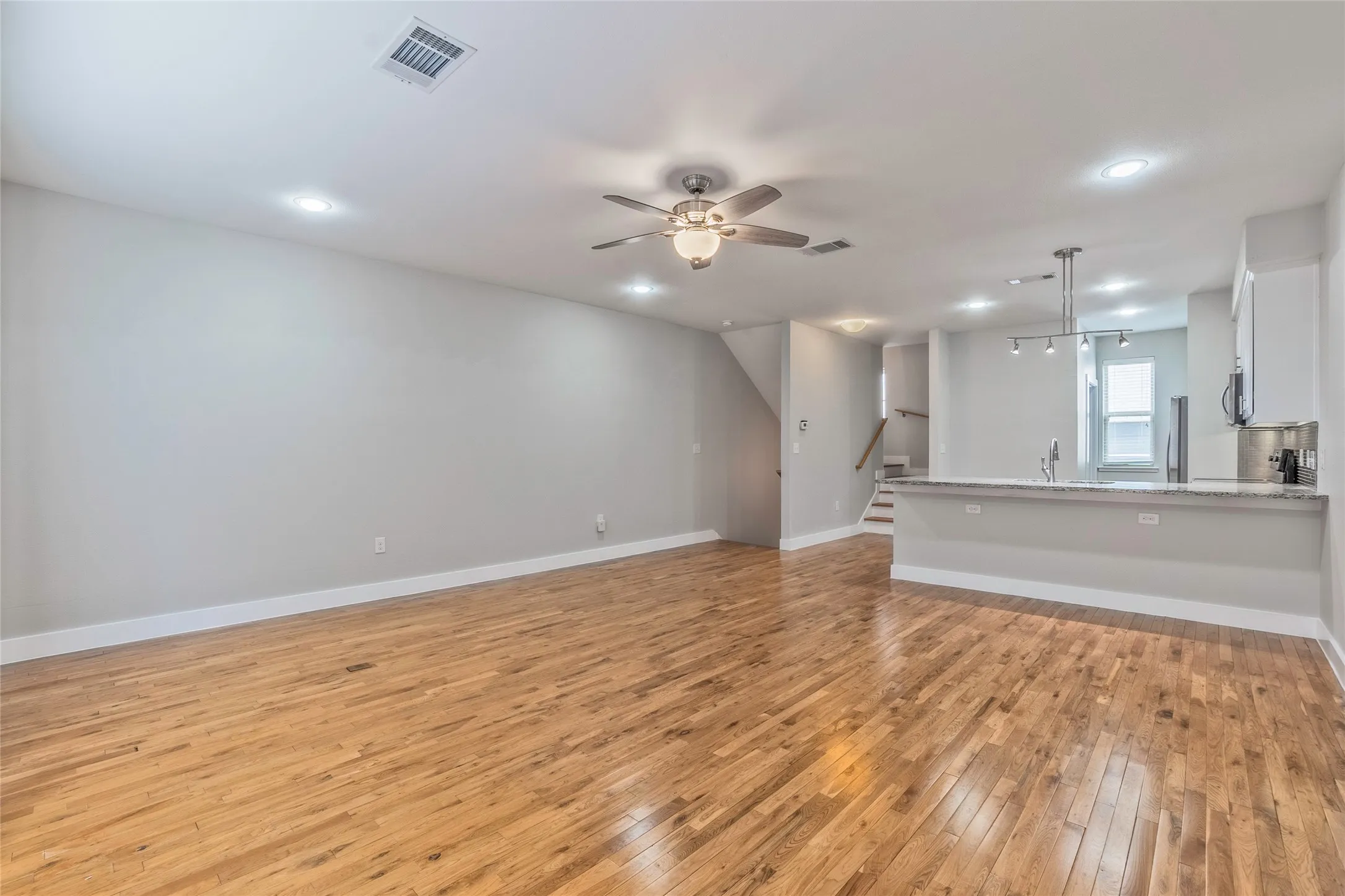 Expansive living area featuring wood-finish flooring, recessed lighting, and a ceiling fan