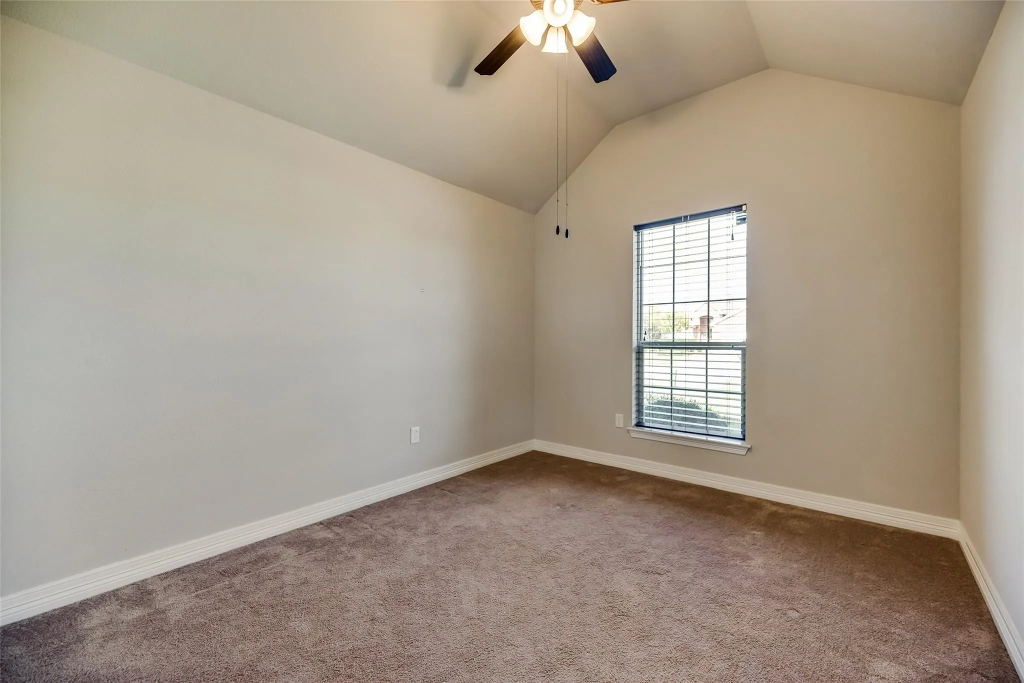 Vaulted ceiling, ceiling fan with integrated lighting, single window with blinds, neutral wall paint, and carpet flooring