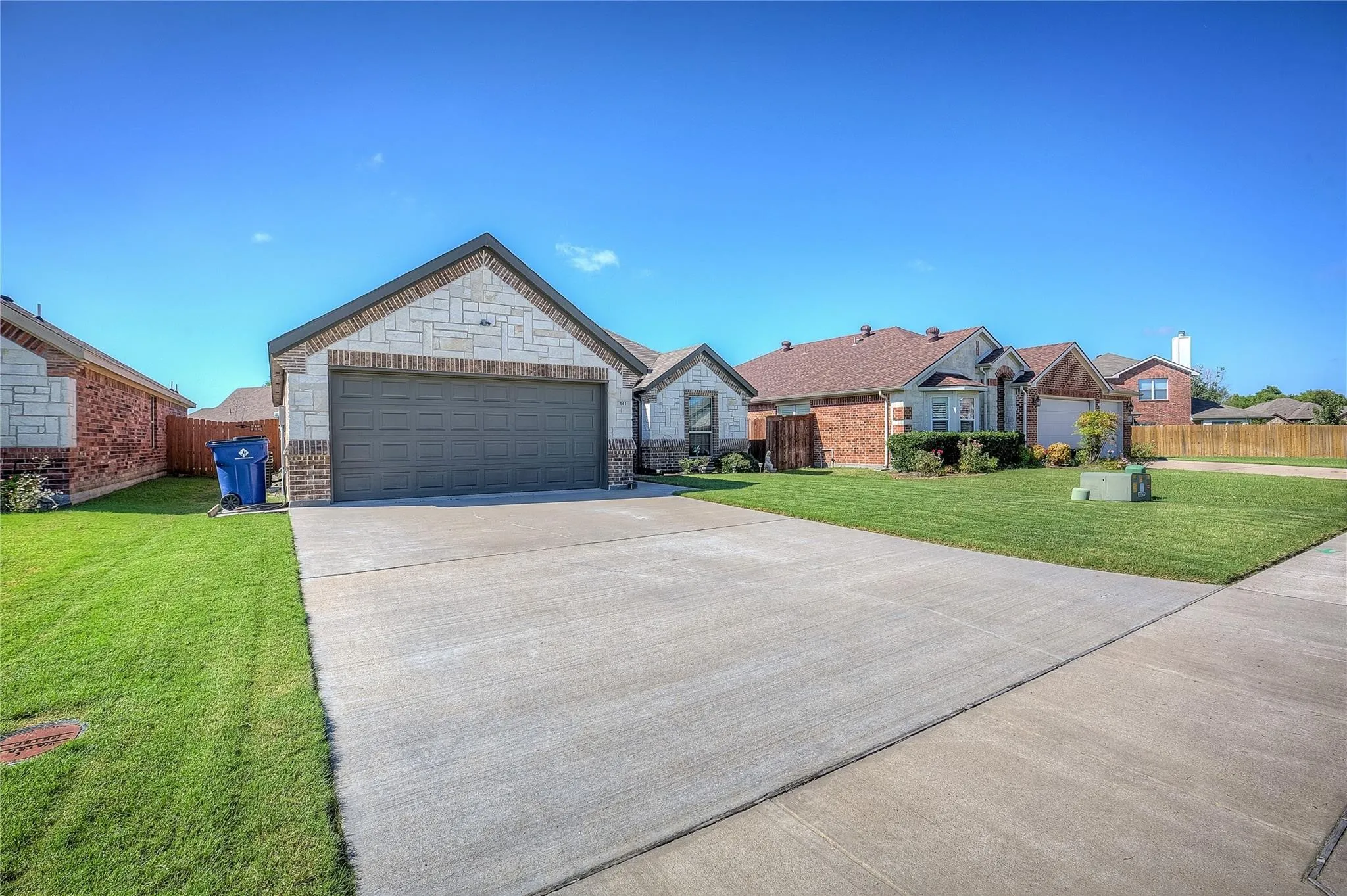 Exterior featuring a combination of brick and stone siding, an attached garage, a concrete driveway, and a maintained lawn