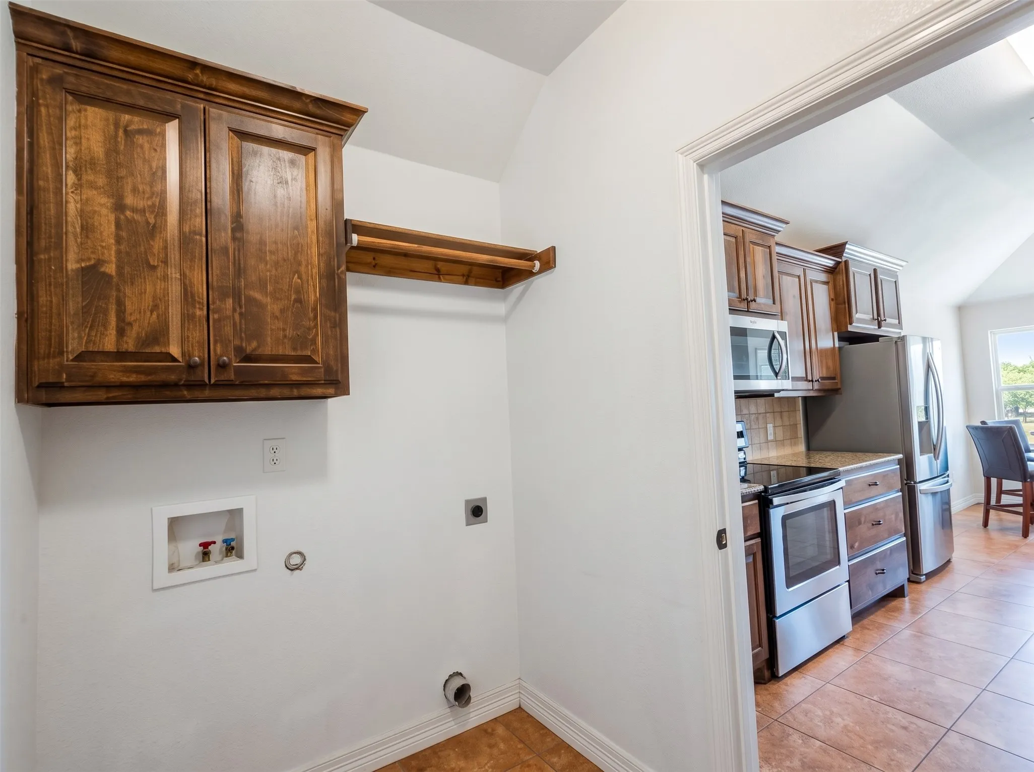 Laundry area with wood-finish cabinetry and a hanging rod