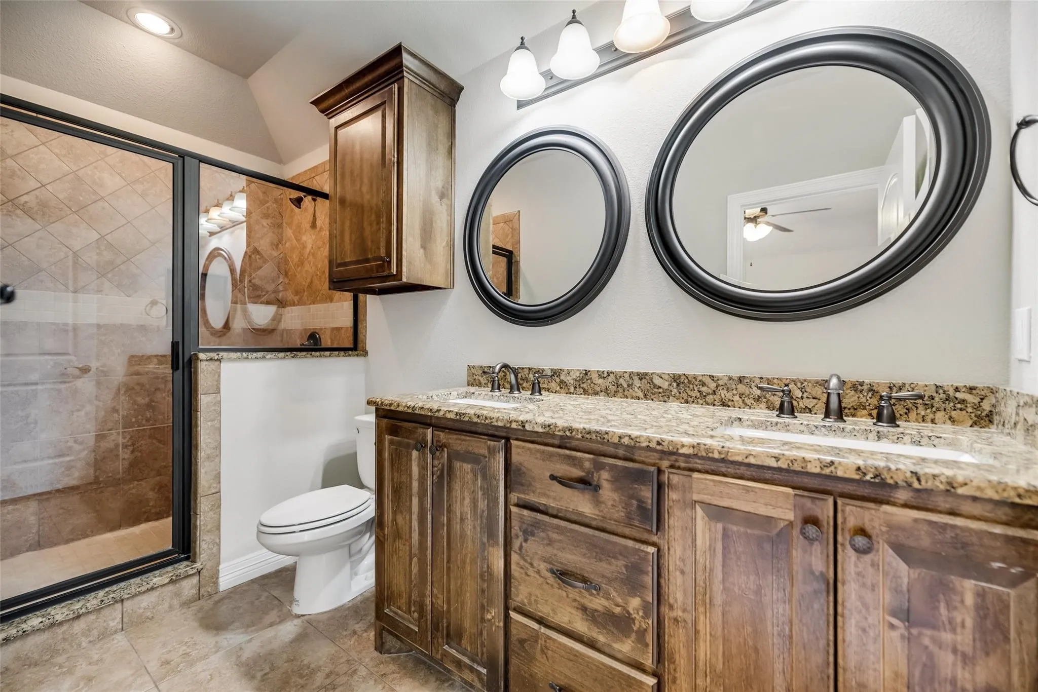 Double vanity with granite countertop, individual basin sinks, and dark wood-finish cabinetry