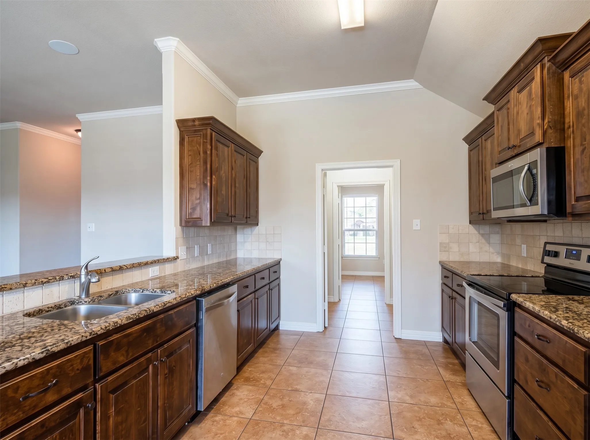 Kitchen featuring wood cabinetry, stainless steel appliances, granite countertops, and ceramic tile flooring