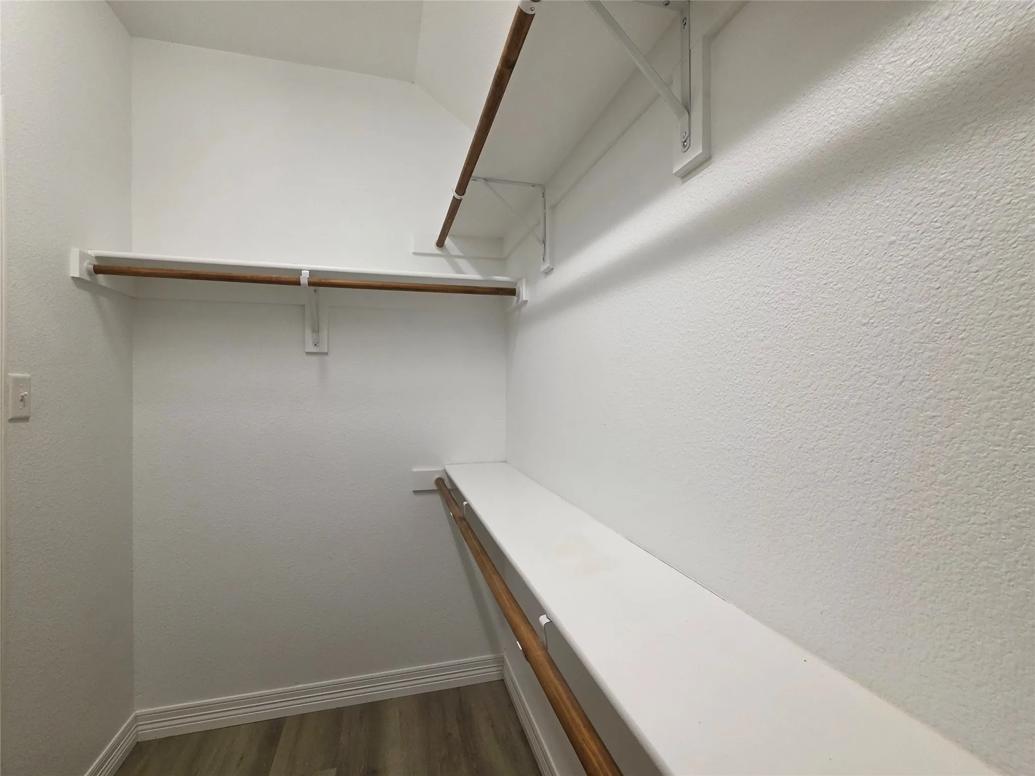 Built-in shelving and hanging rods with wood-finish flooring