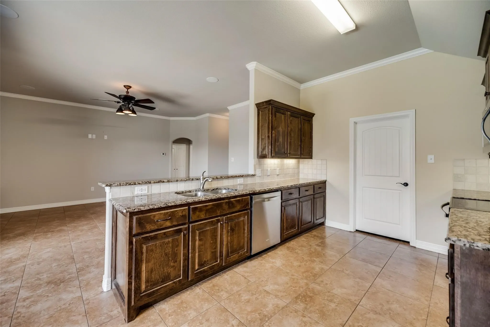Kitchen featuring wood cabinetry, granite countertops, tile flooring, and a stainless steel dishwasher