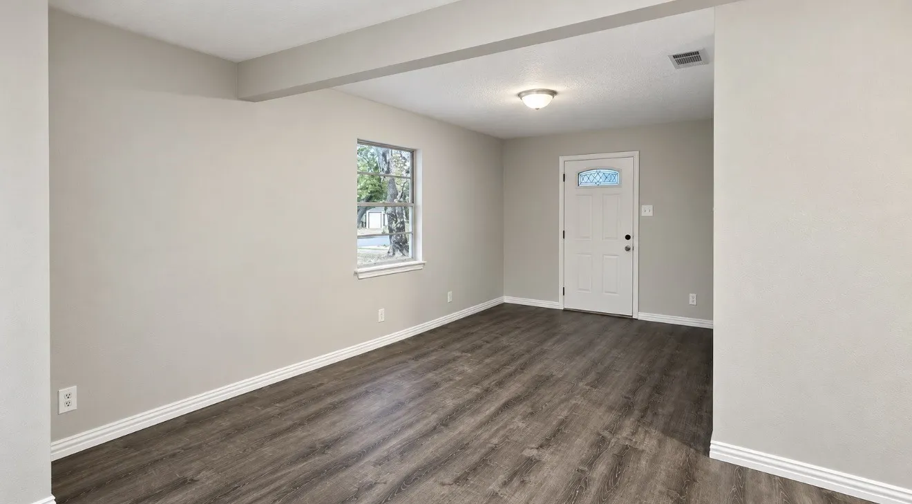 Entry area featuring vinyl-finish flooring, neutral wall tones, a front door with decorative glass, and a flush-mount ceiling light fixture