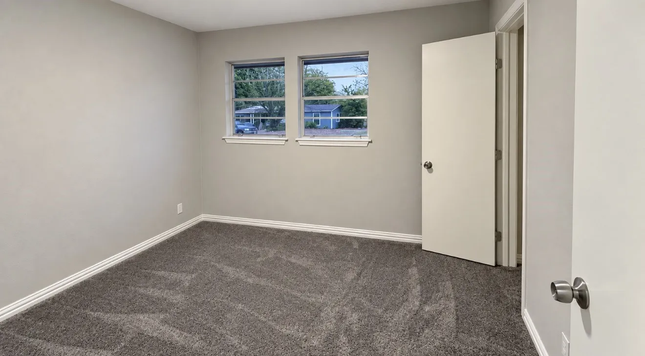 Neutral wall color, two windows, textured carpet, white trim, and a white interior door