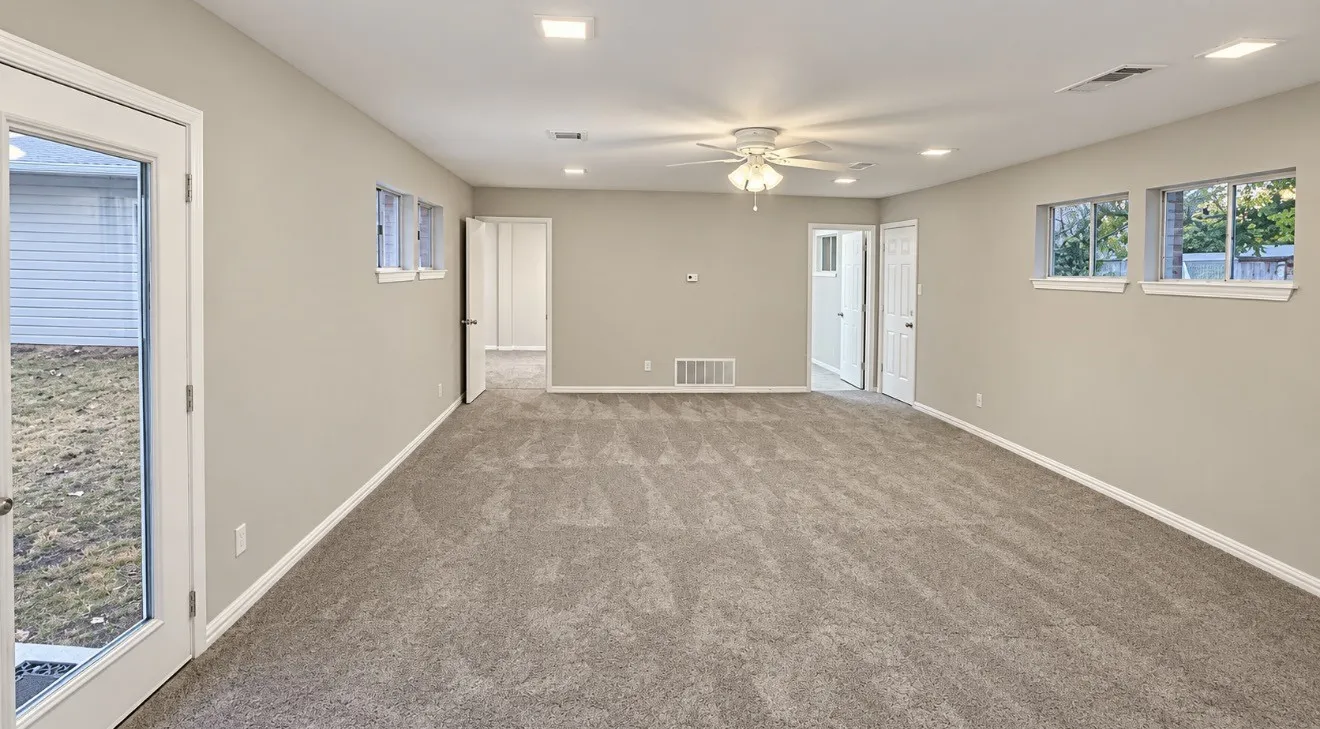 Spacious room featuring gray carpet, recessed lighting, ceiling fan, and multiple windows
