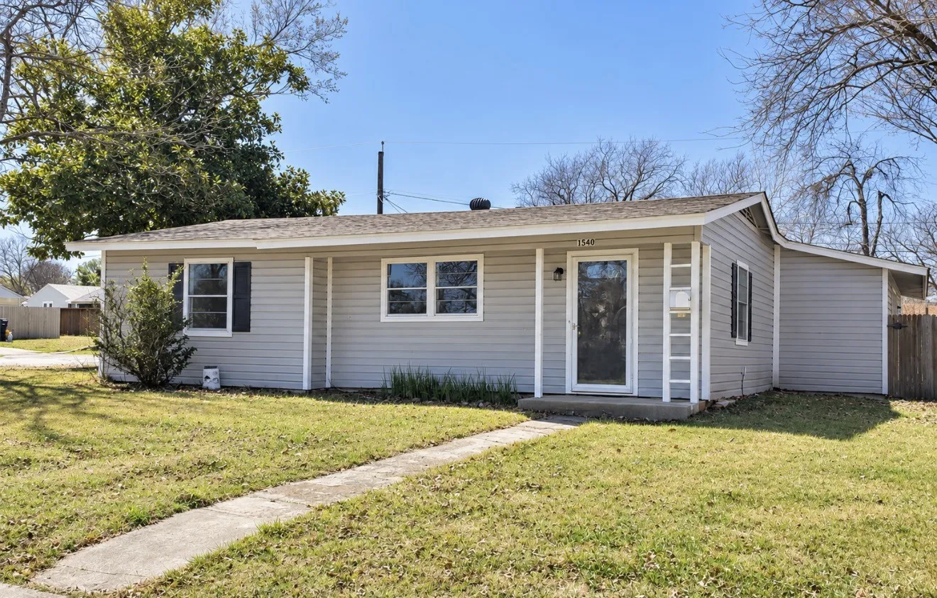 Single-story residence featuring light gray siding, a covered front porch, and a concrete walkway