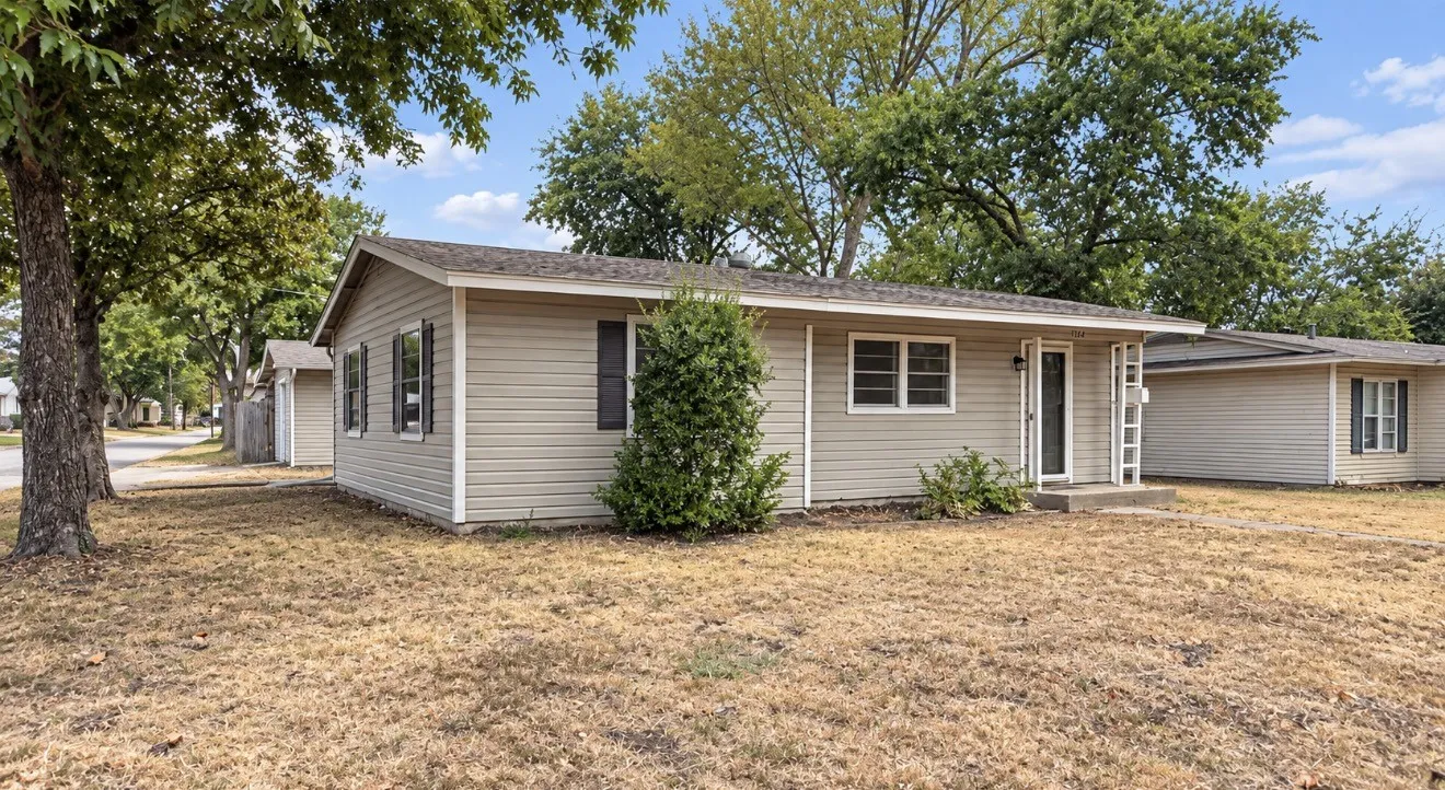 Light-colored siding exterior with dark shutters, covered entry, and a concrete patio