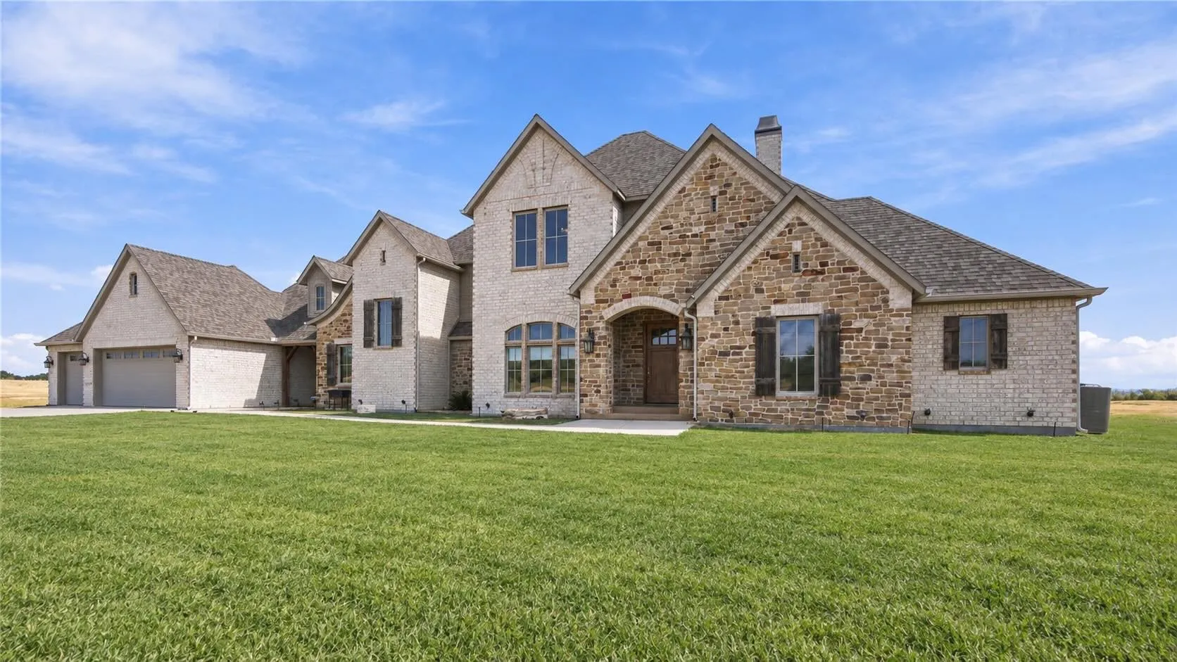 A striking multi-gabled roofline and generous garage space highlight this home's timeless stone-and-brick architecture.