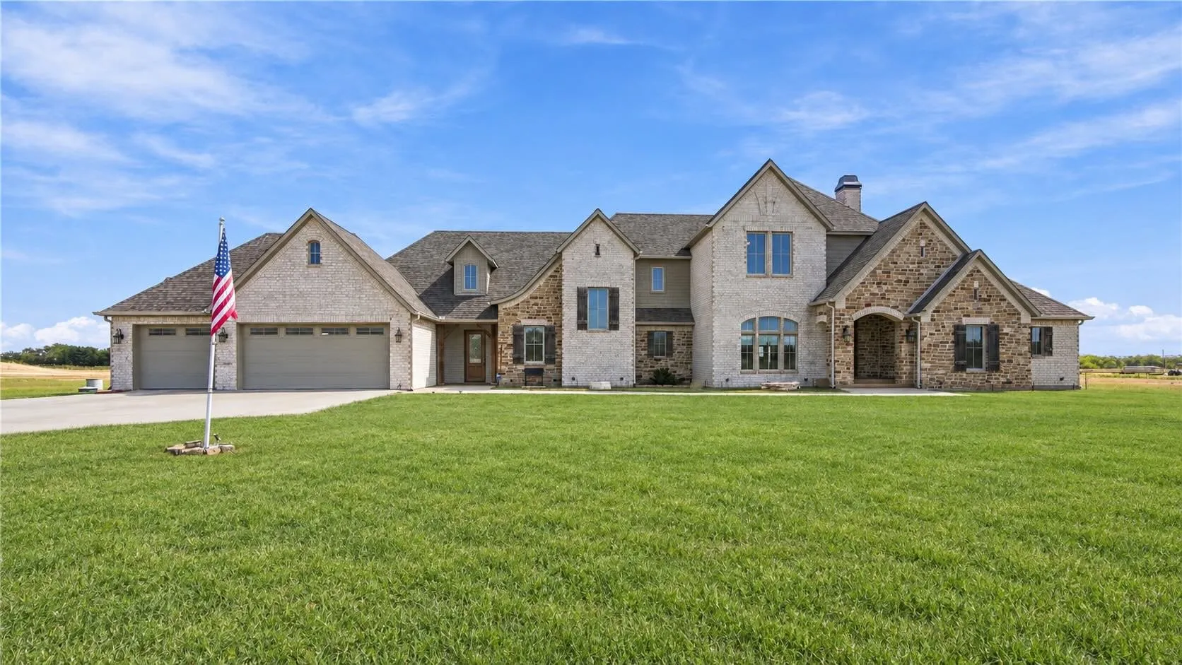 Charming brick-and-stone exterior with gabled rooflines and dormer windows framing an inviting arched entry.