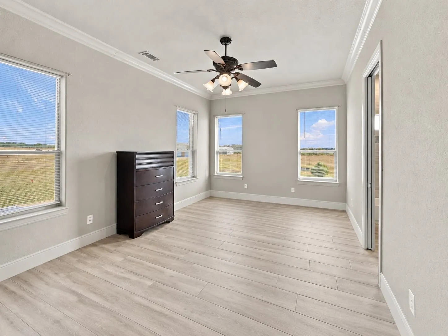 A bright secondary bedroom with crown molding and multiple windows, great for family, guests, or a home gym.