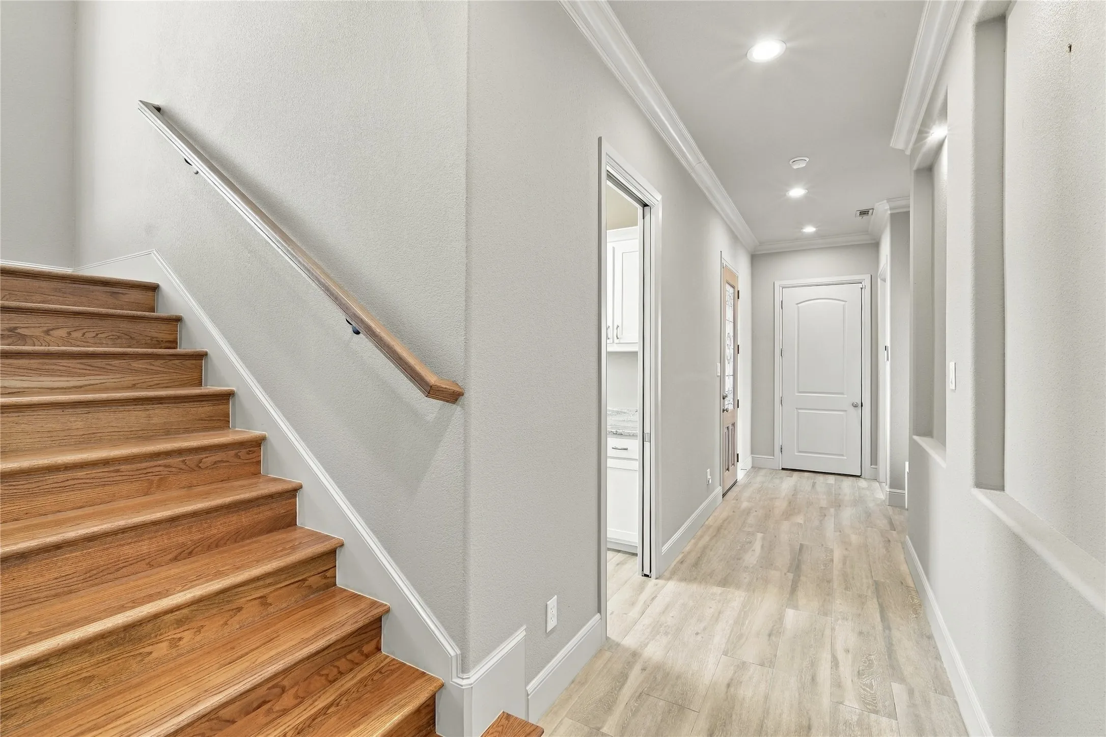 A handsome wood handrail staircase overlooks the tile flooring below, framed by crown molding.