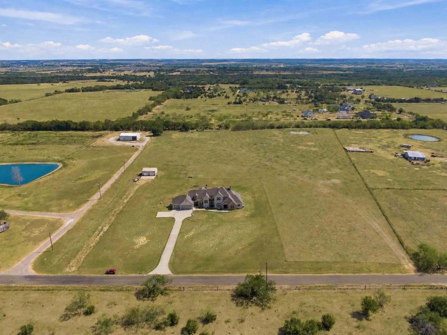 An aerial glimpse of the full property, home, outbuildings, and a private pond, all set along a paved driveway.