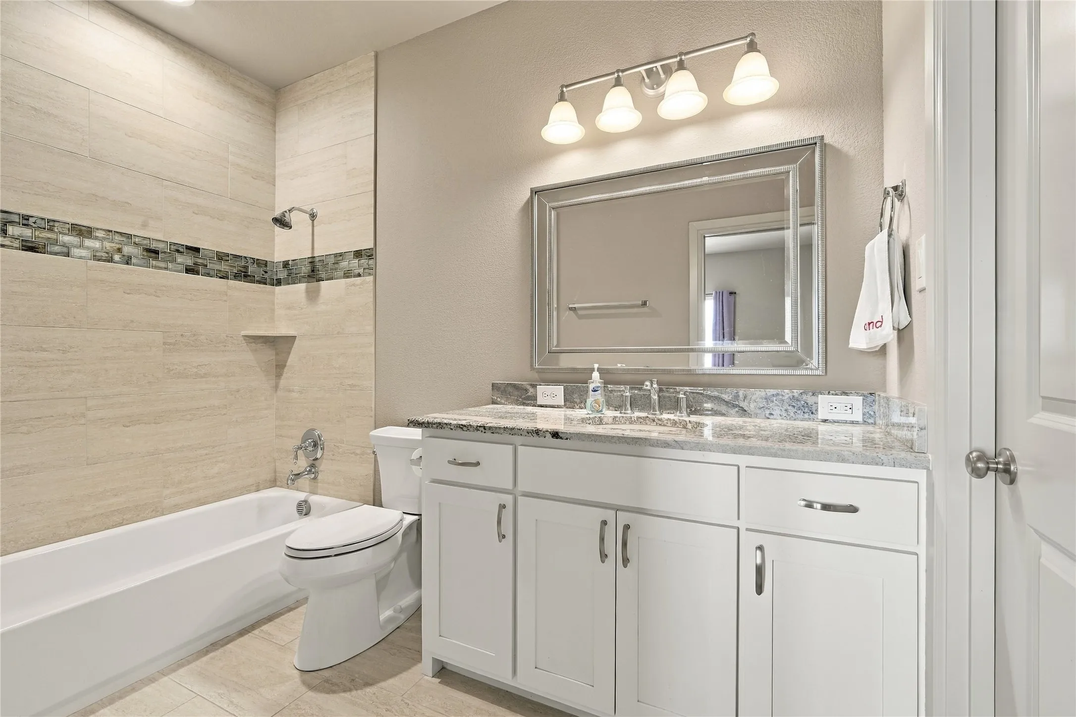 A tiled tub surround with mosaic accents adds a spa-like touch to this secondary bath.